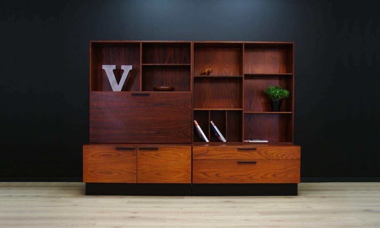 Brilliant system by Ib Kofod Larsen, sensational form from the 1960s-1970s consisting of a cabinet, a bookcase and a bar. A Classic form covered with rosewood veneer. The front has four spacious drawers and an illuminated bar. Two shelves behind the