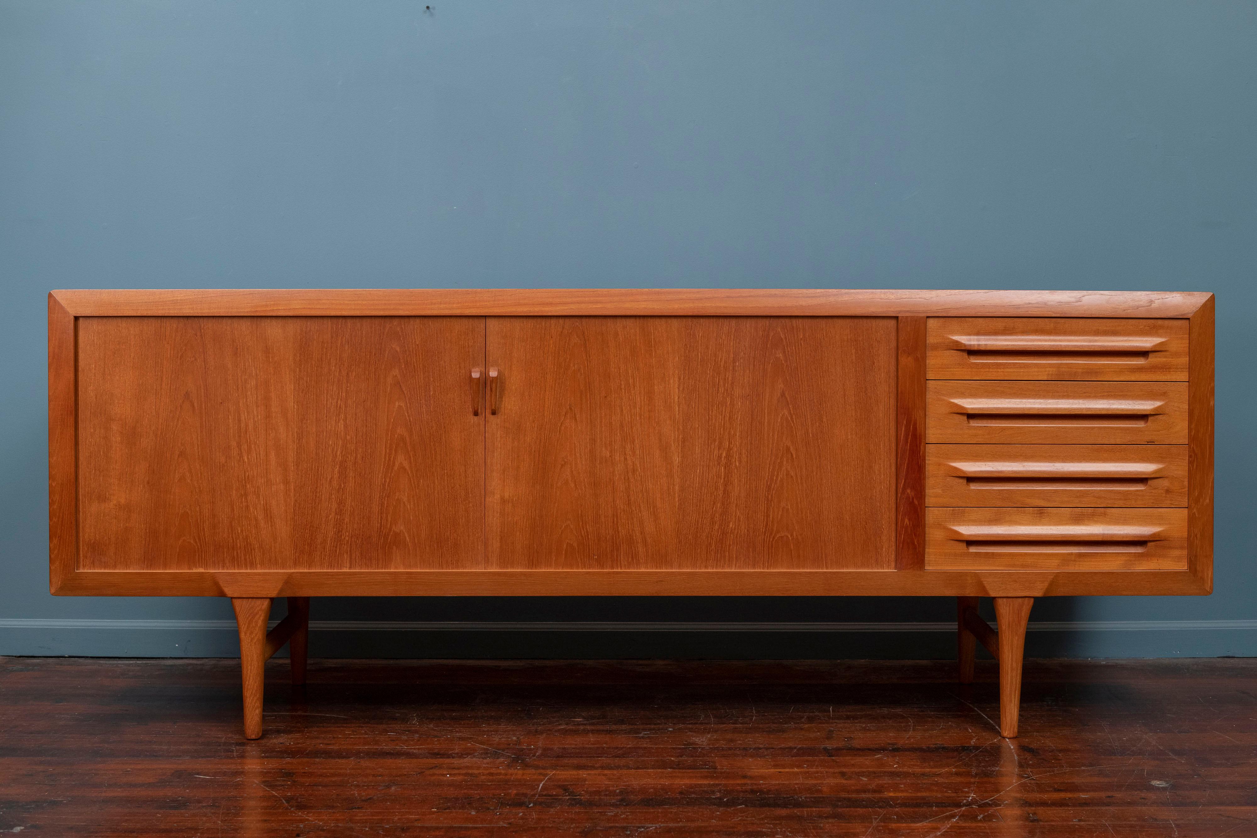 Tambour door credenza designed by Ib-Kofod Larsen for Faarup Møbelfabrik in Denmark, circa 1950s. Impeccably crafted in teak wood, this beautiful credenza shows an intricate wood grain throughout and features smoothly functioning tambour doors that