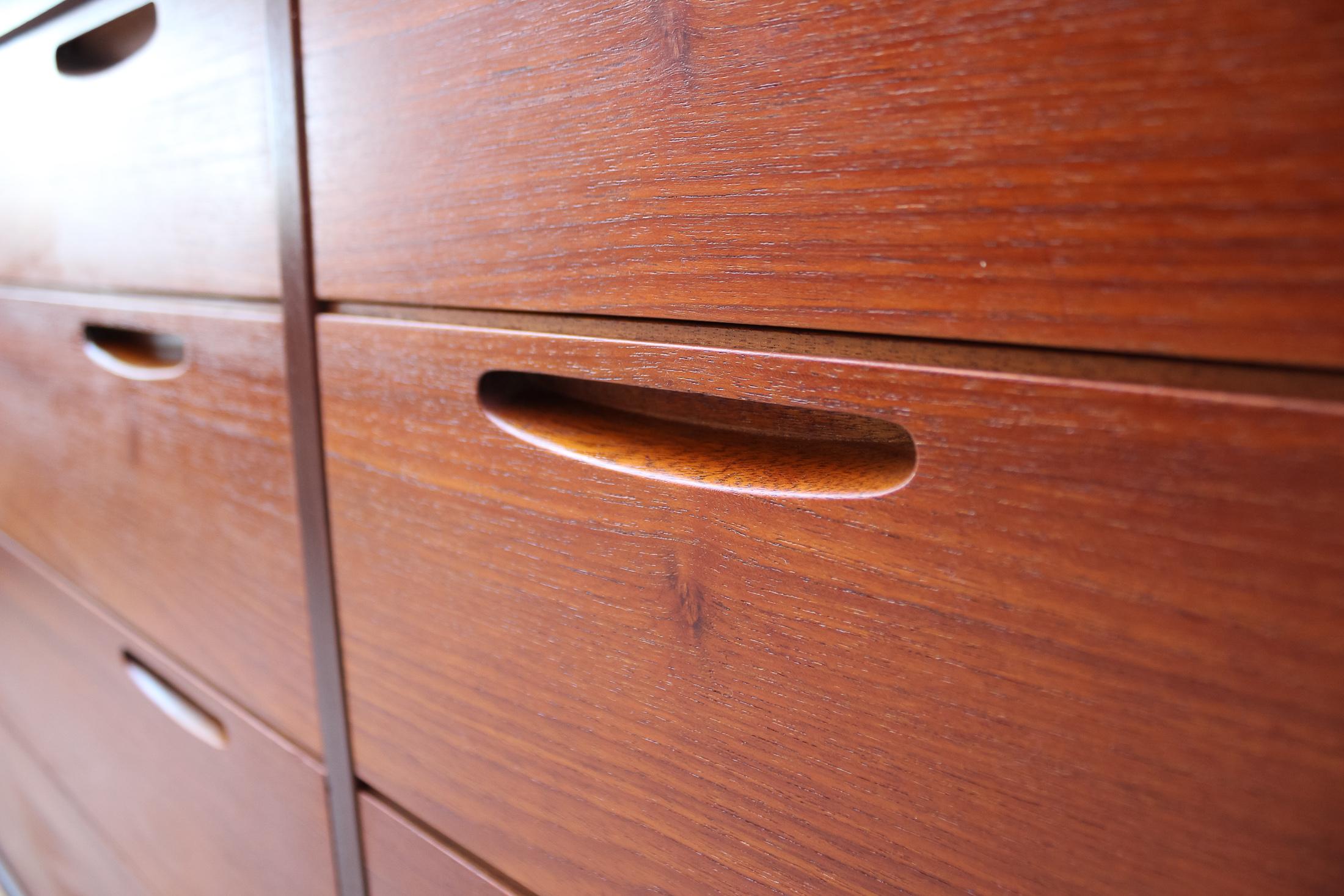 The Ib Kofod-Larsen Teak 8-Drawer Credenza, crafted by the esteemed Brande Mobelfabrik, is a stunning example of mid-century modern design. Dating back to the mid-20th century, this piece is an excellent representation of the minimalist, functional