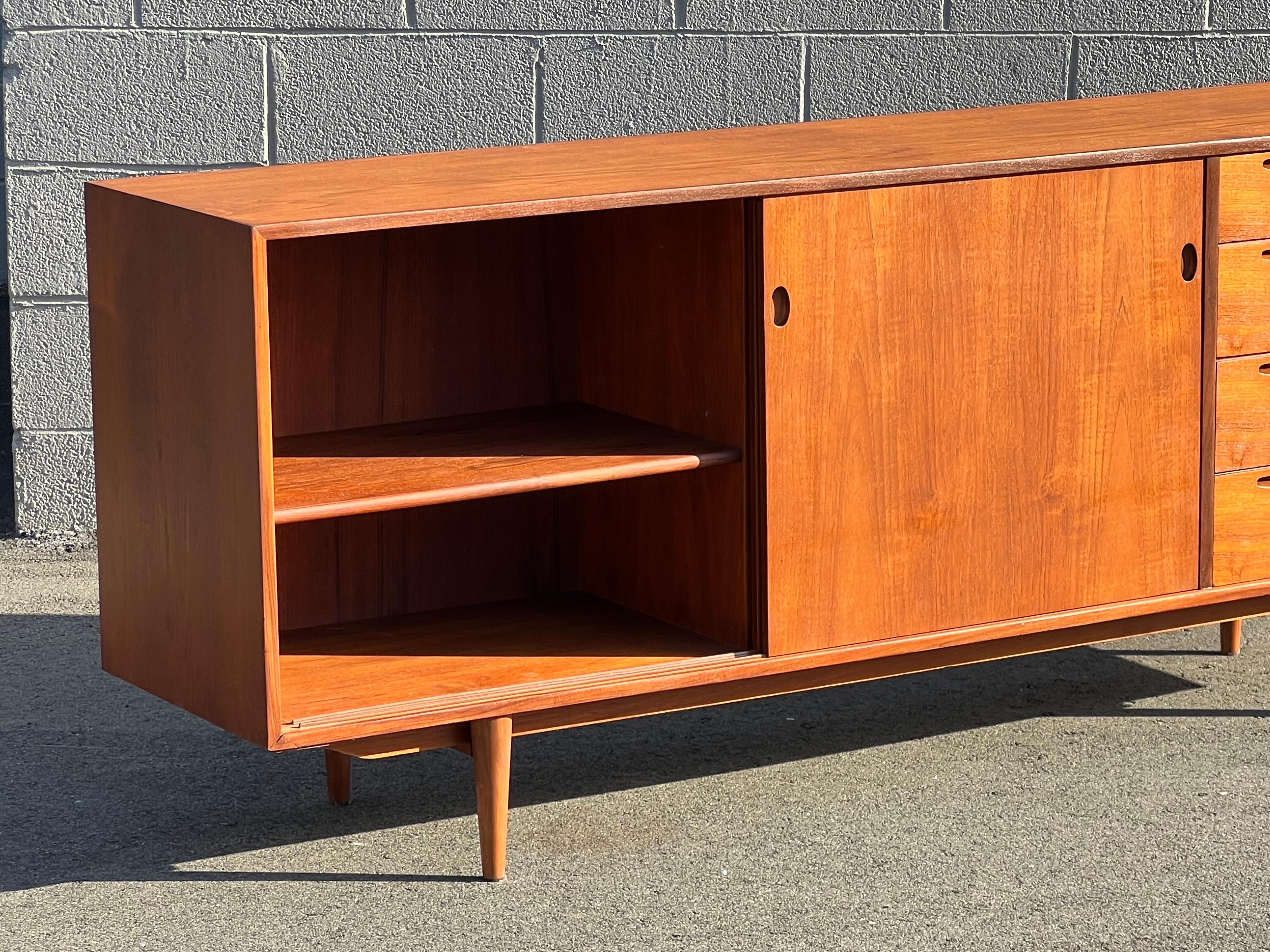 Mid-century rare teak credenza designed by Ib-Kofod Larsen for Clausen and Sons, Denmark. Equipped with two smooth sliding doors, four visible drawers, and two interior drawers. This credenza really hones in on the details. The door and drawer