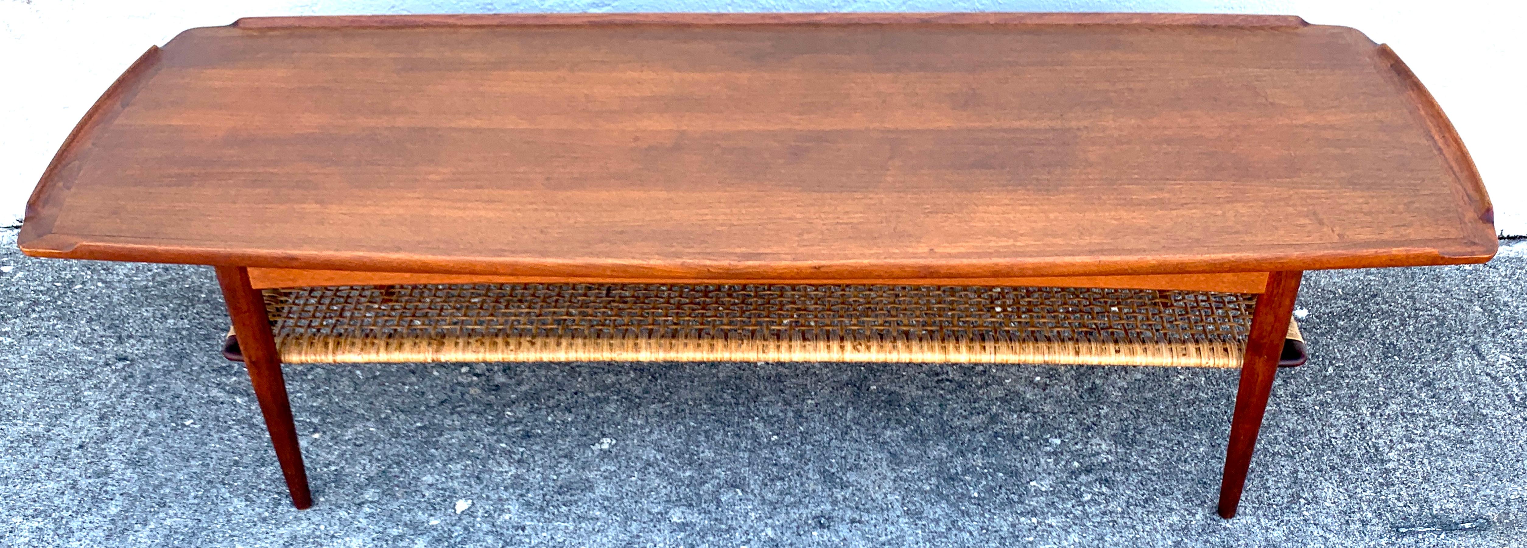 Two-tier teak surfboard coffee table with caned shelf, by Ib-Kofod Larsen, With canted corners with subtle partial gallery edge, with a beautiful handwoven caned
45