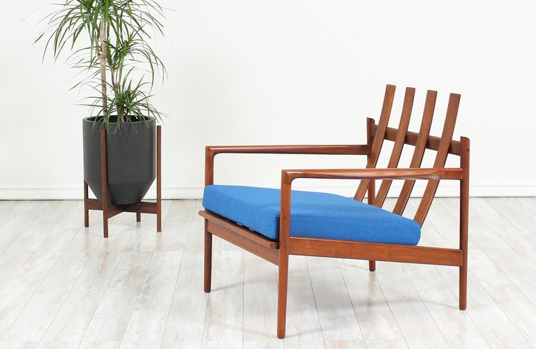 Stunning lounge chair designed by Ib Kofod-Larsen for Selig in Denmark, circa 1960s. This distinctive Danish modern design features a solid walnut wood frame with four large slats acting as the backrest plus comfortable, carved armrests. The