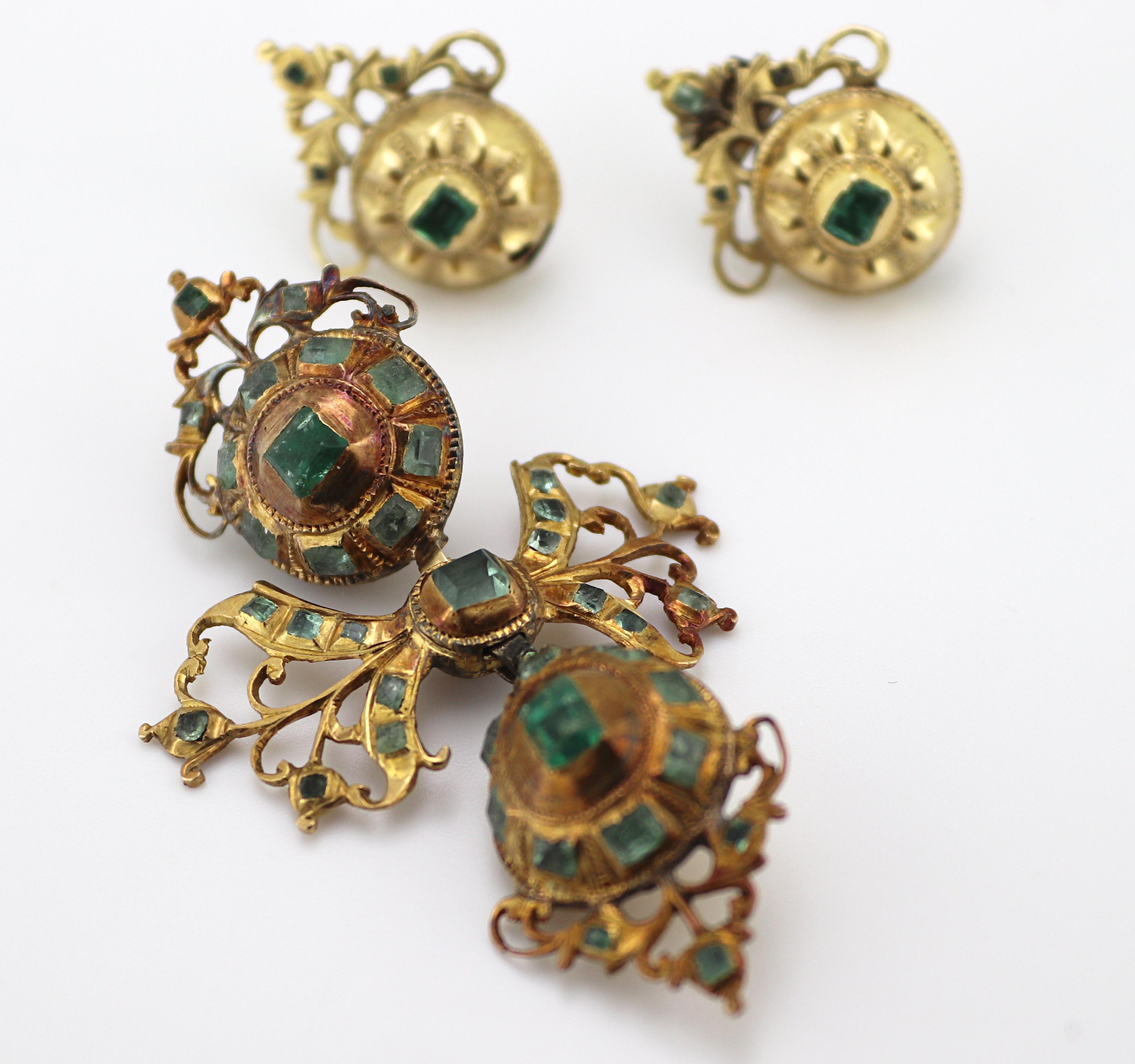 Including one Latin lace cross, accented throughout by (38) table-cut
emeralds and green beryl, set in a hand fabricated 15k yellow gold
articulated link mounting, 57.9 X 35.5 X 13.6 mm; accompanied by a
matching pair of buttons and scroll earrings