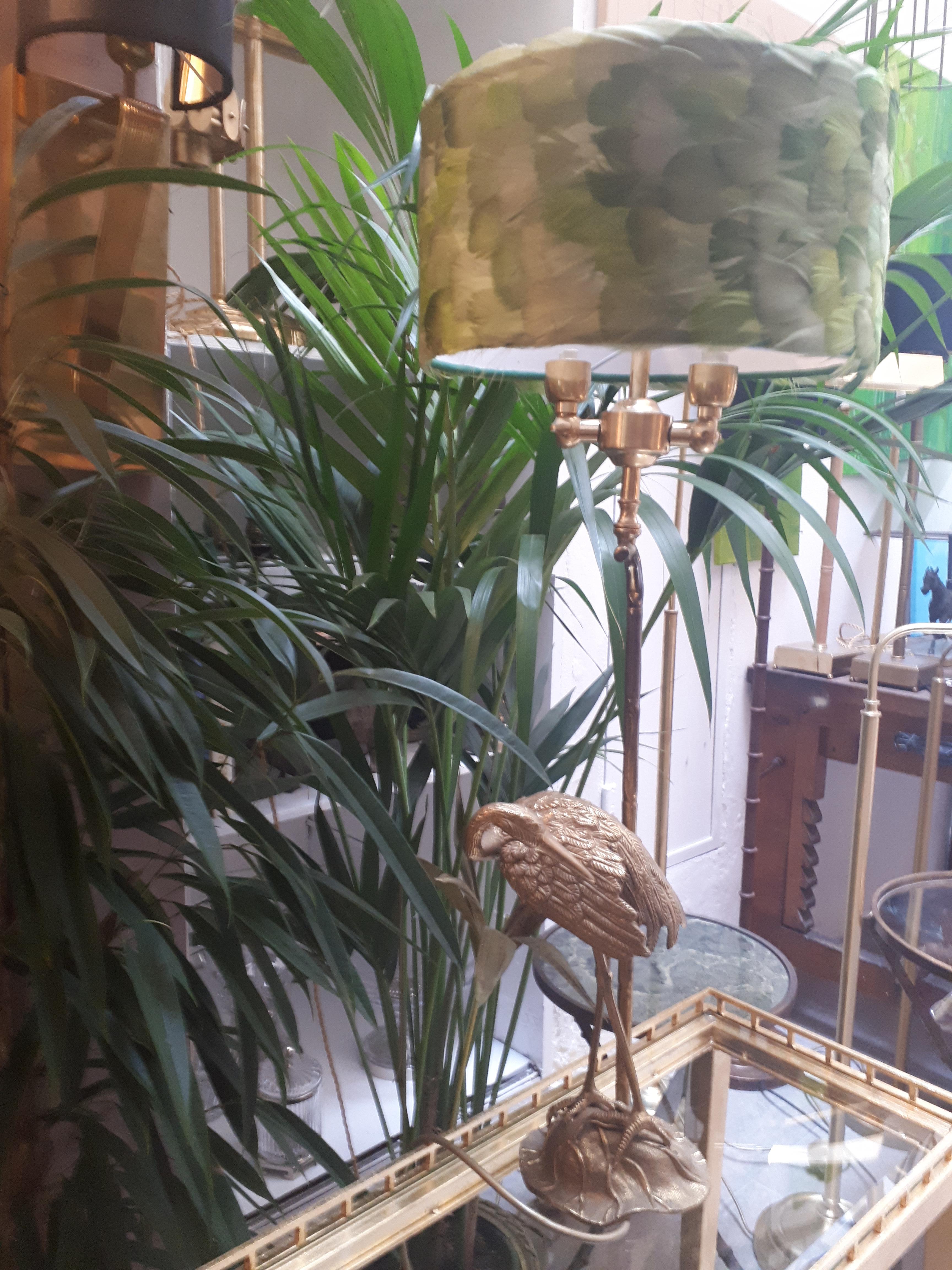 Fauna 05_A est une élégante lampe de table dont la structure en laiton moulé reproduit, avec des détails extraordinairement fidèles, un Ibis dans son environnement naturel et dont l'abat-jour est entièrement recouvert de véritables plumes colorées