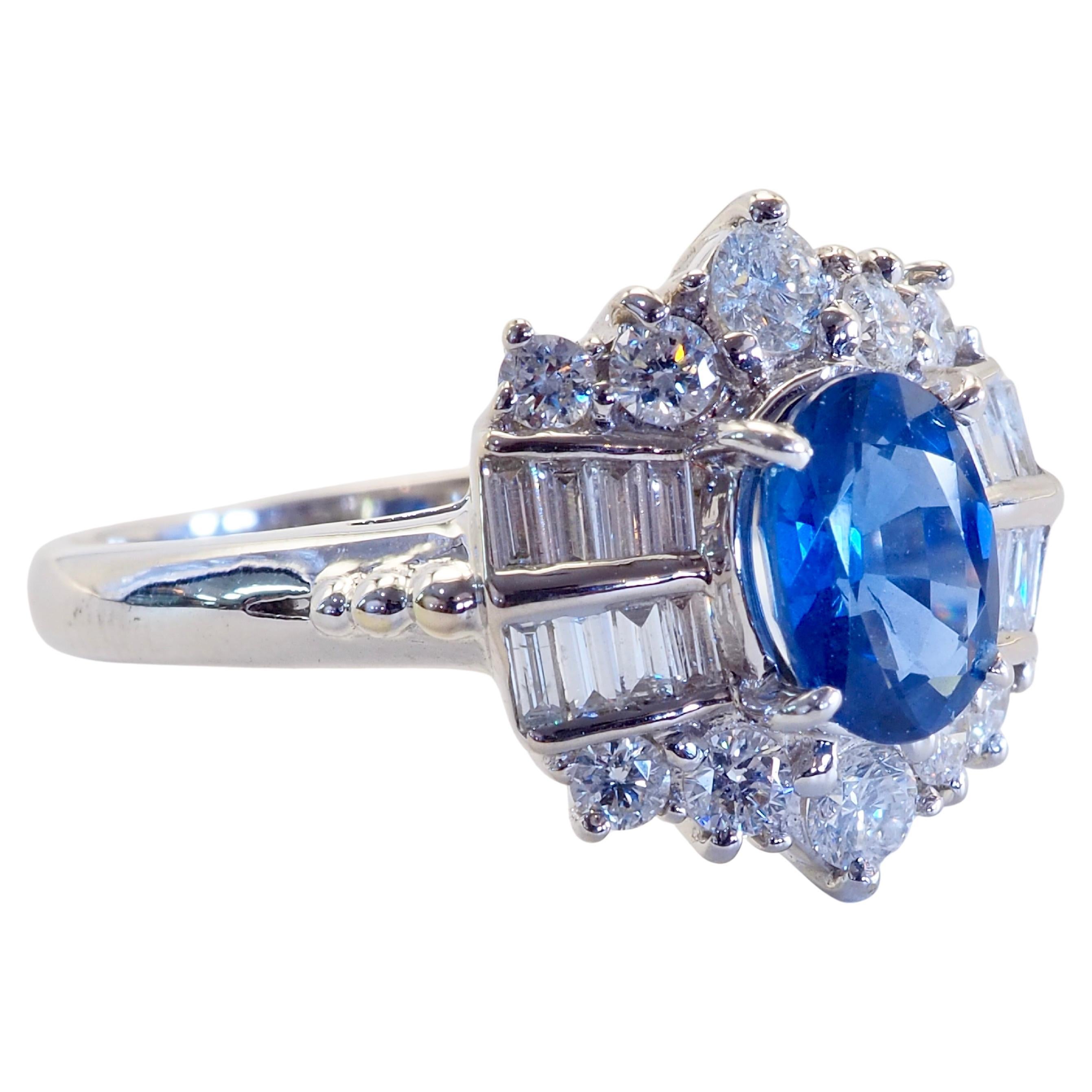 Étonnante et élégante bague à grappe légère qui se targue d'un saphir bleu bleuet d'une beauté unique. Le saphir ovale est d'une taille de 1 carat mais d'une couleur bleu clair unique et impressionnante. Des diamants brillants et baguettes de grande