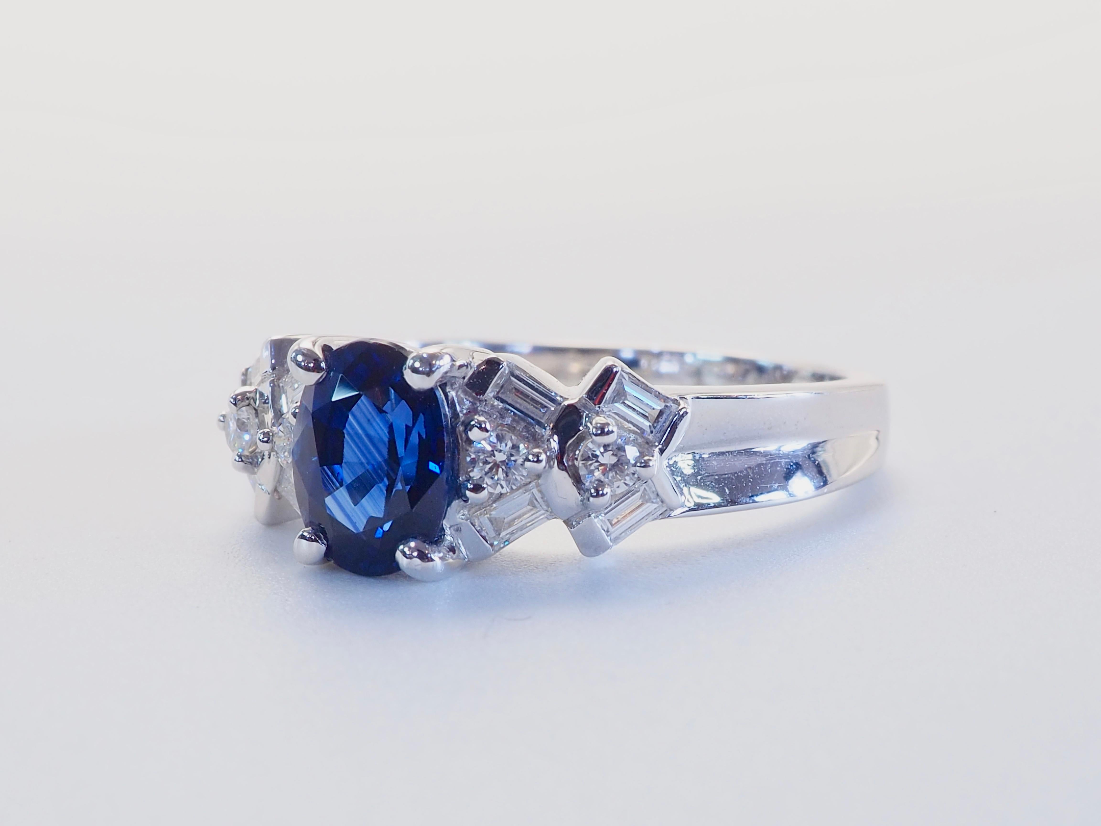 Ein leuchtender blauer Saphir im Ovalschliff von 1,20 Karat ist das Herzstück dieses eleganten Rings aus 18 Karat Weißgold. Flankiert von acht Diamanten im Baguetteschliff und vier Diamanten im Brillantschliff mit einem Gesamtgewicht von ca. 0,26