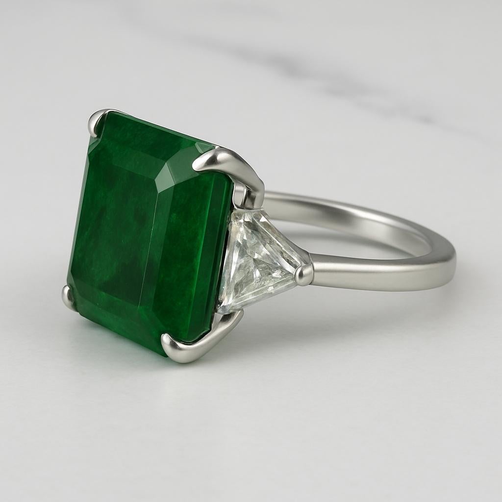 A magnificent platinum ring showcasing a certified 14.25-carat Zambian emerald with a rich, saturated intense green hue. This exceptional gemstone has undergone only minor oil clarity enhancement, a highly desirable and rare treatment level for