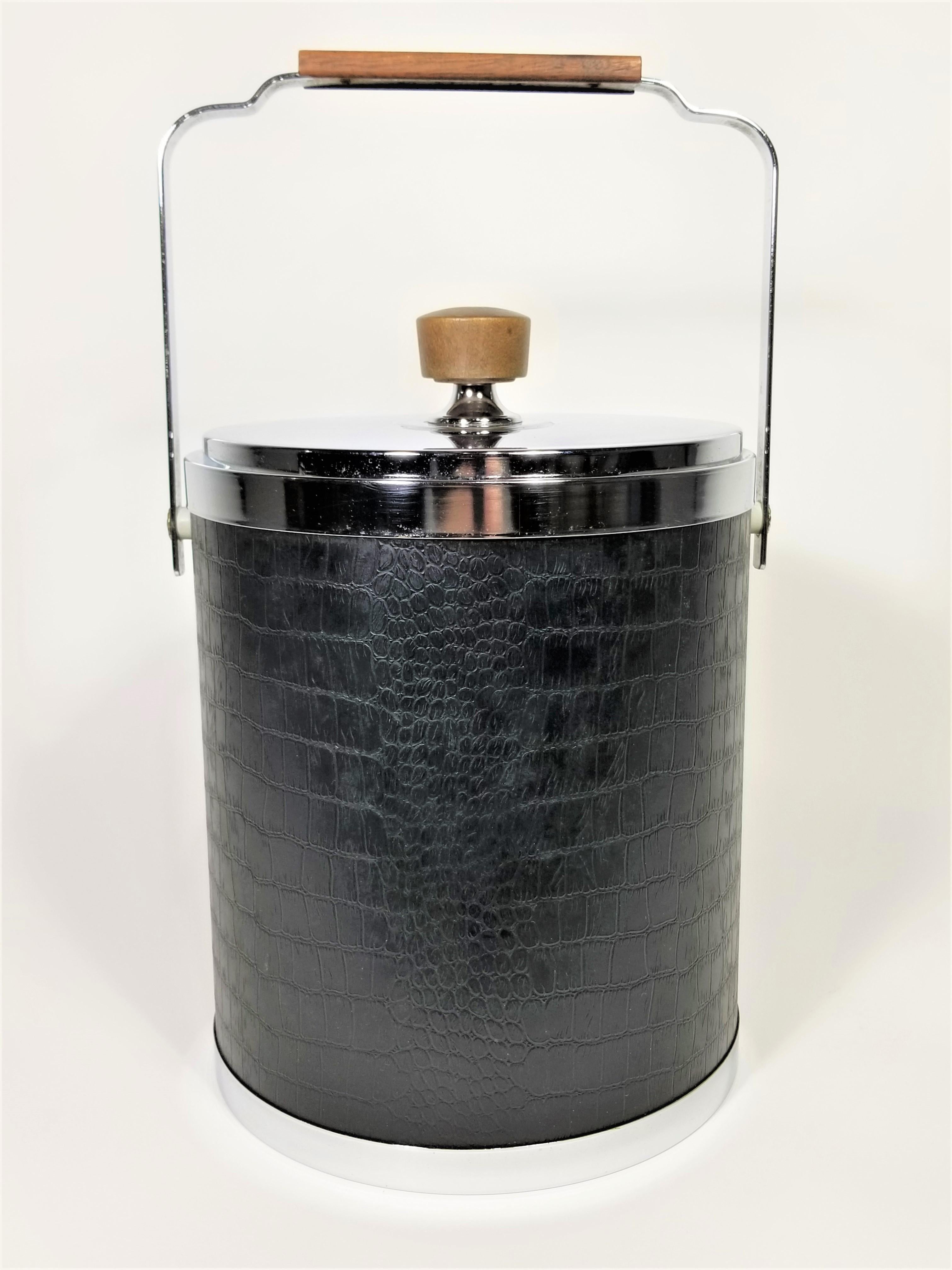Midcentury 1960s ice bucket. Chrome with black alligator embossed design vinyl. Ice bucket with walnut handles.
Measurements:
Height handle down: 11.5 inches
Height handle up: 15.0 inches
Diameter of bucket (outside): 8.25 inches
Width
