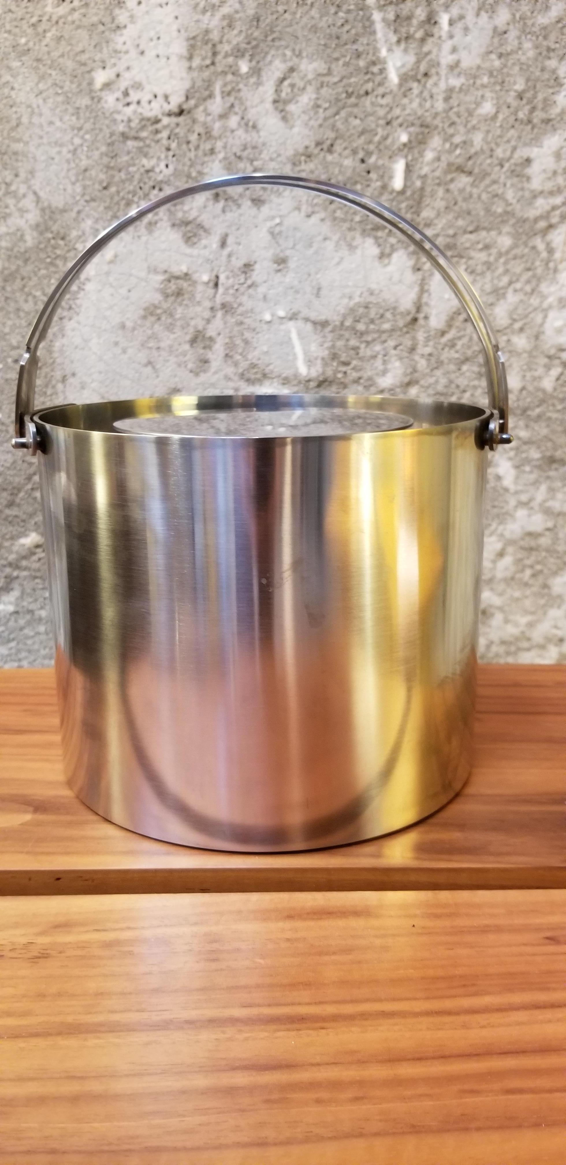 Vintage stainless steel ice bucket with tongs designed by Arne Jacobsen for Stelton. Both pieces signed. Bucket with handles lowered measures 5.75 inched tall.