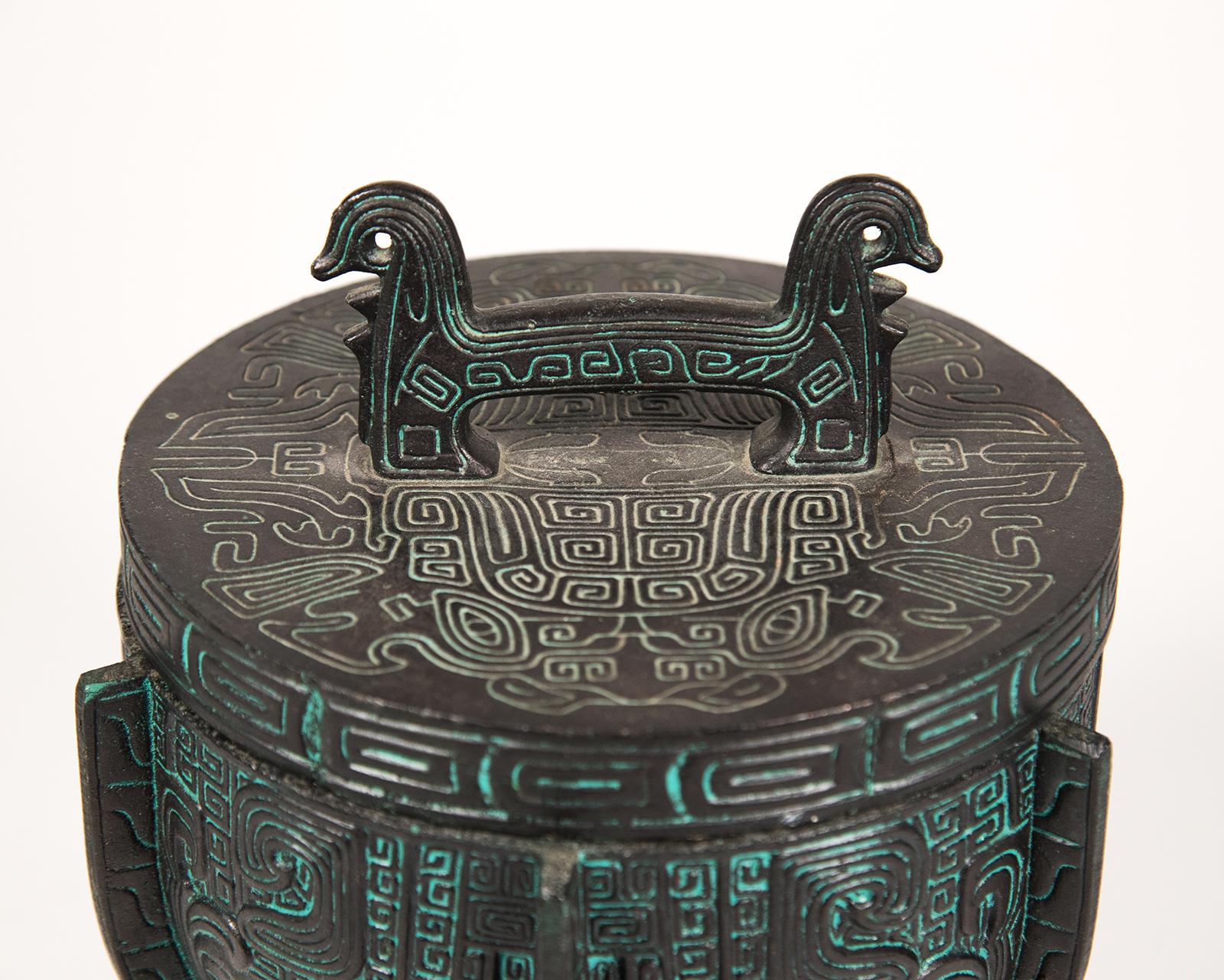 Ice bucket in the style of James Mont. The faux cast lid and body in an antiqued bronze finish in an Aztec motif. The liner is stainless steel.