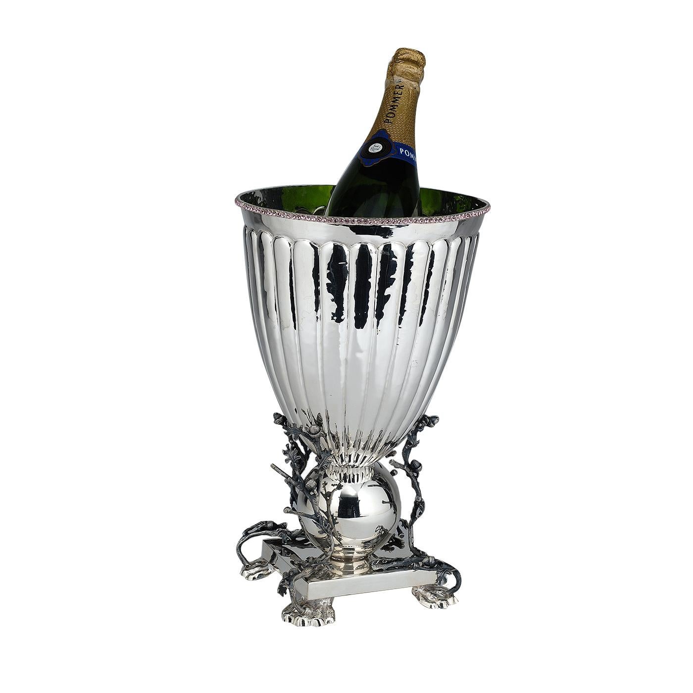 This elegant and timeless ice bucket can also be used to chill bottles of wine. Its classically inspired shape rests on a squared base that is supported by four lion paws. Its body is adorned at the bottom with a sphere that is decorated with