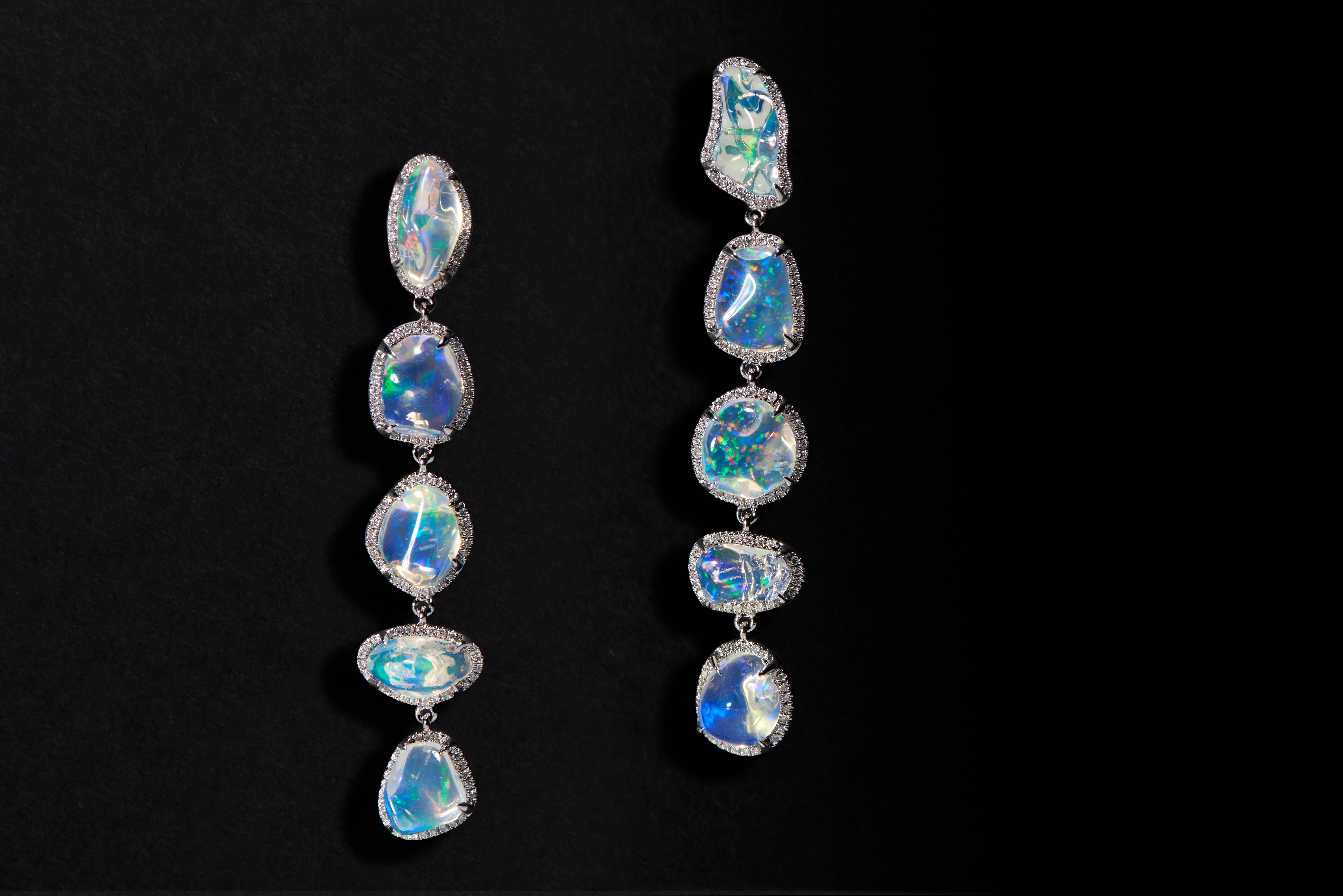 A dazzling chain of irregular shaped opals create a play of light and reflection, vividly rendering ethereal hues of blues, greens, and purples in Ri Noor's Ice Drops Linear Clear Fire Opal and Diamond Earrings. Evoking the contemporary jewelry