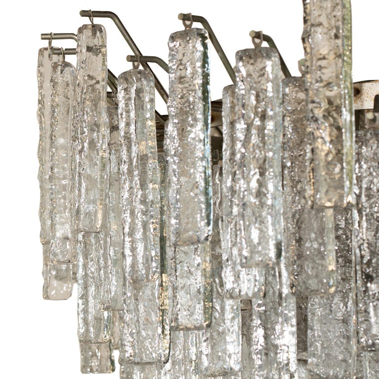 This stunning “ice” glass multi level chandelier is adorned with over 150 pieces of thick figured Murano glass. It takes 6 light bulbs so it can shine brightly in any room! Wired for North America.
