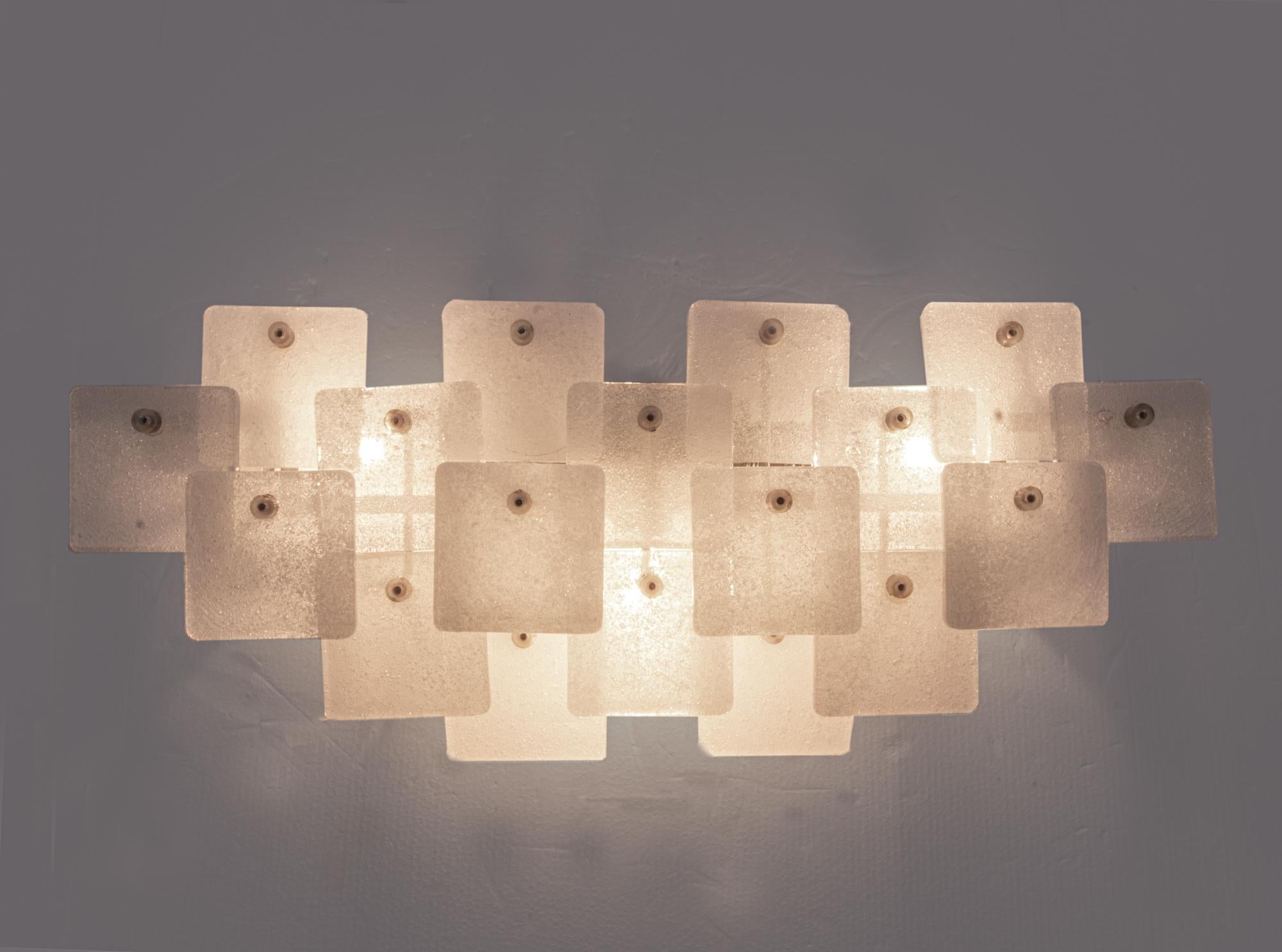 Elegant iced glass wall fixture made of thick foam Murano glass elements mounted on a white laquered nickel frame. The sconce is documented in the Kalmar catalogue from 1970. The eighteen square shaped and foamed Murano glass elements are mounted