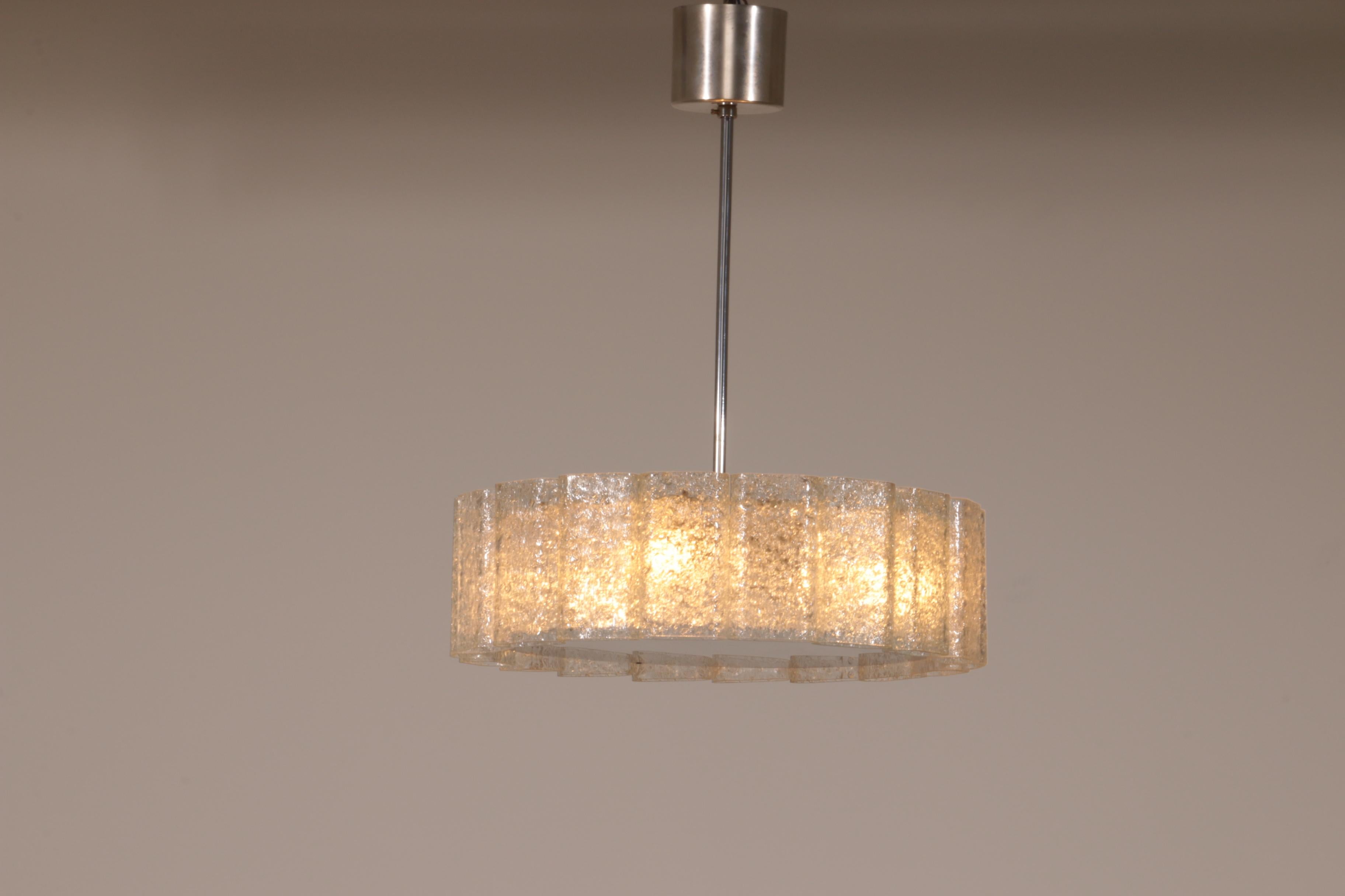 Questa è una lampada a sospensione in vetro di ghiaccio molto bella.

Queste bellissime lampade a sospensione sono state prodotte negli anni '60 da Doria Leuchten.

Le lampade sono composte da 18 grandi cilindri di vetro soffiato a bocca,