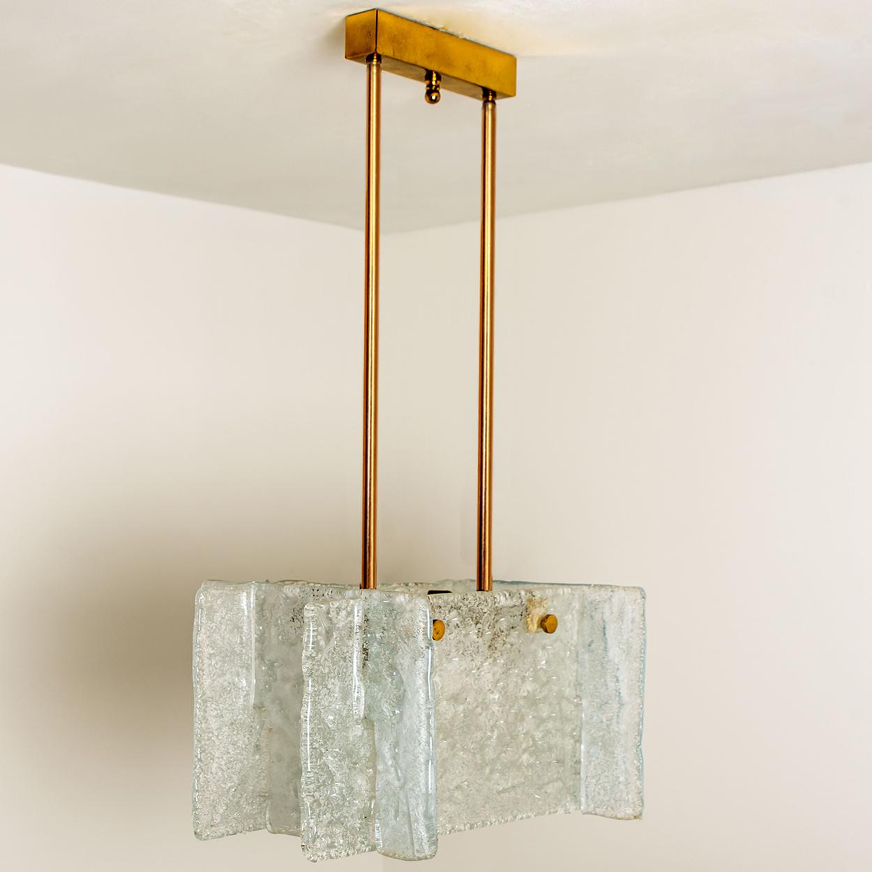 An ice glass pendant light designed by J.T Kalmar, manufactured by Kalmar Franken, Austria in the 1960s.
High-end and handmade design from the 20th century. The pendant/chandelier has four textured glass shades. Together they form a rectangular
