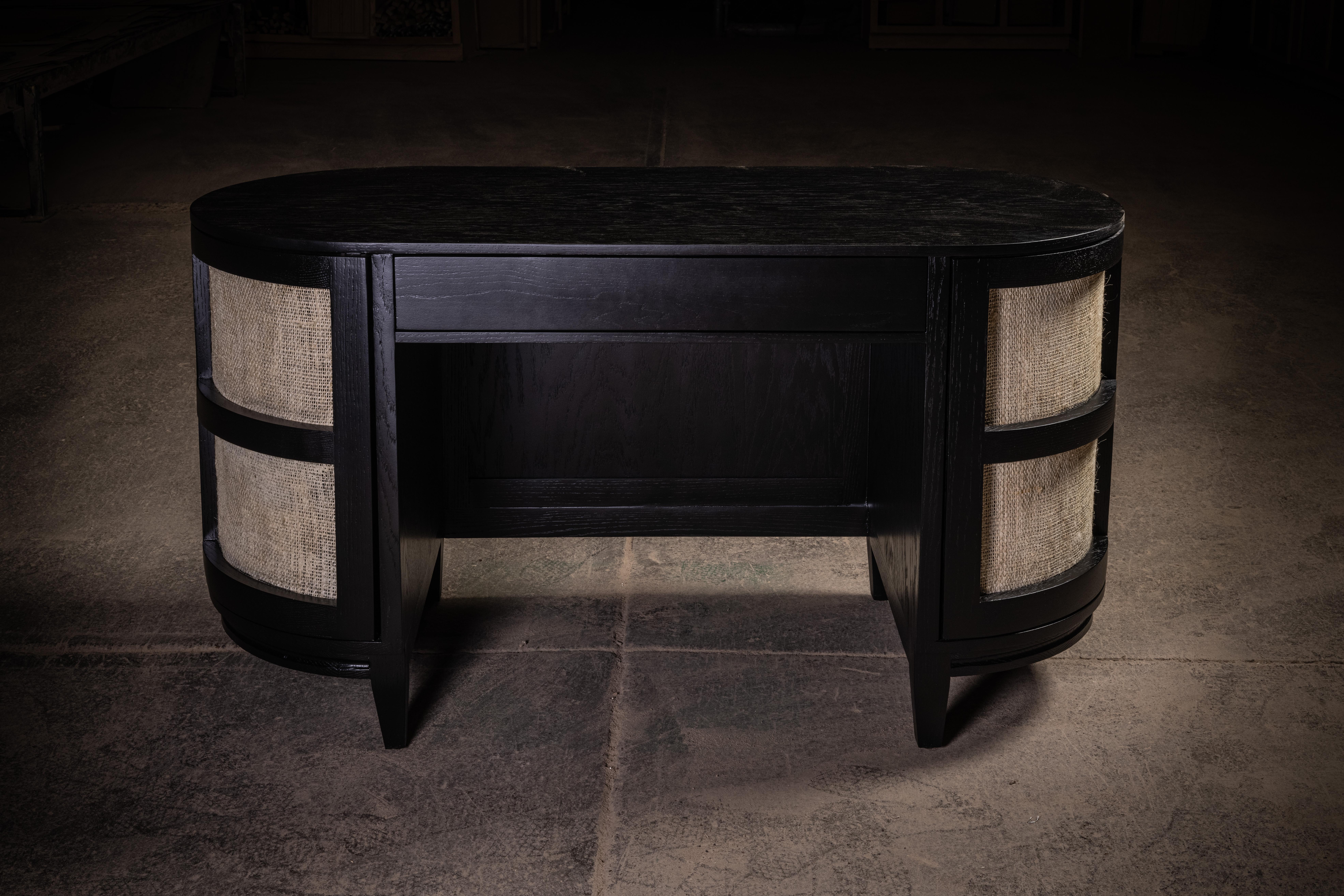 Modern, oval black solid oak desk with 2 doors covered with Ixtle and a center drawer.