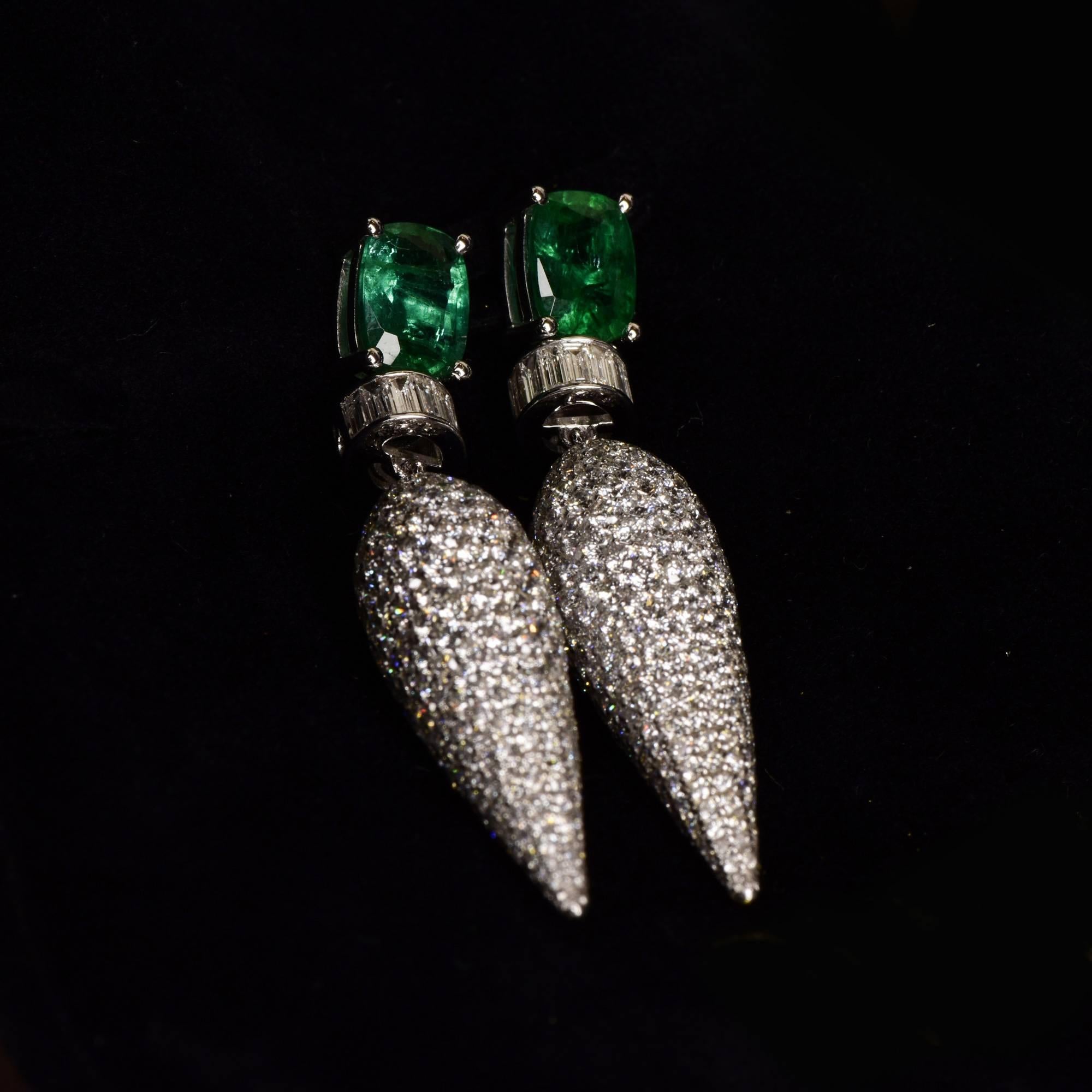 Icicle motif dangler earrings with unenhanced emerald and round brilliant diamonds. This dramatic earring features an icicle of pave diamonds hanging from the ear that dazzles with its stunning play of light. The captivating earrings boldly blend