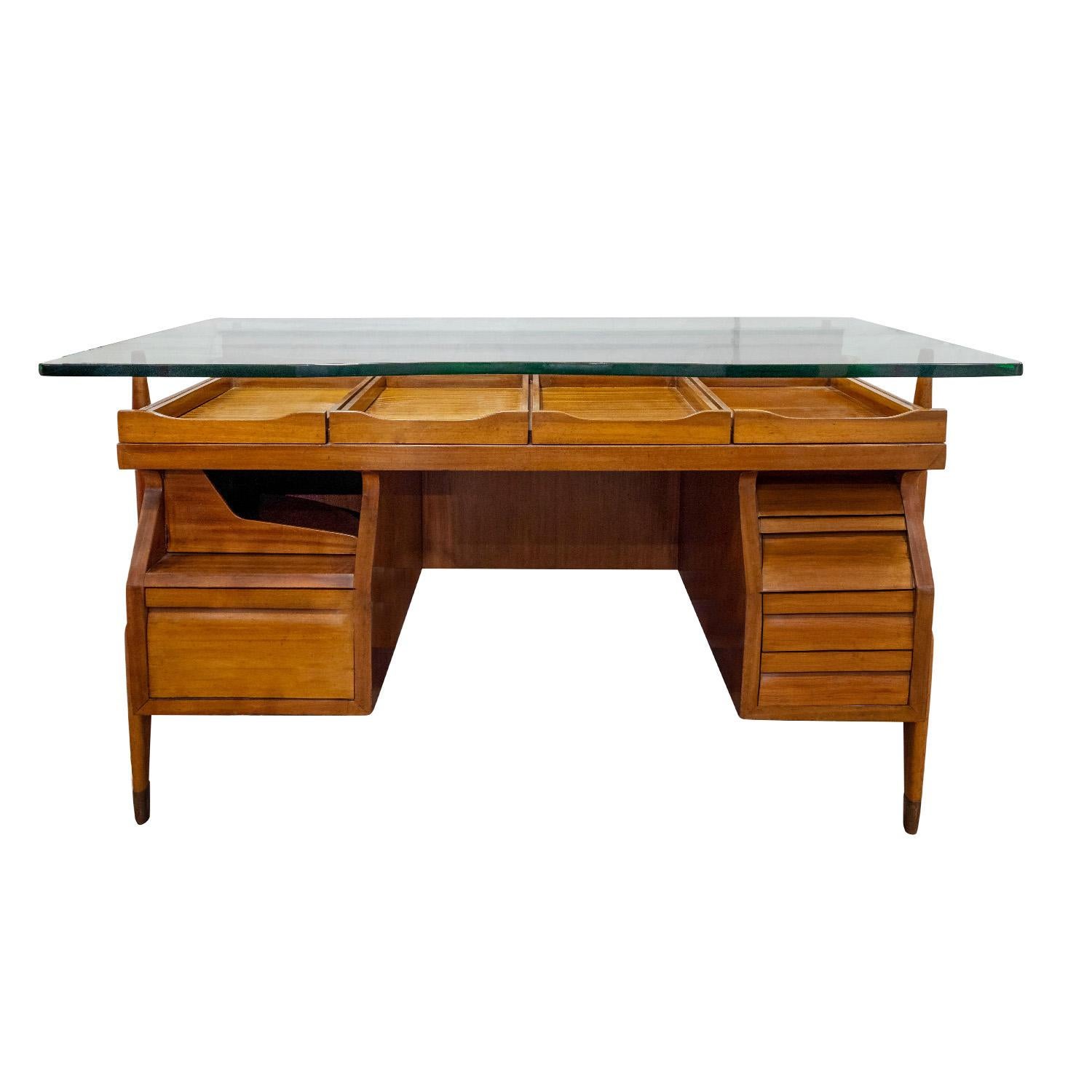 Architektonischer Schreibtisch aus Nussbaumholz mit skulpturalen Beinen mit Messing-Sabots und schwebender, dicker Glasplatte, zugeschrieben von Ico Parisi, Italien, 1950er Jahre.  Dieser Schreibtisch ist mit Schubladen, ausziehbaren Fächern und