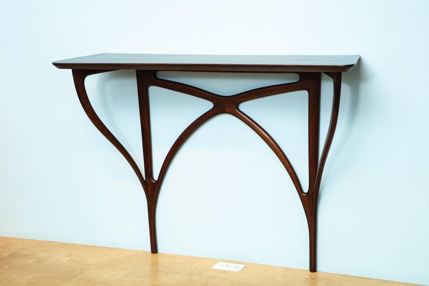 Rare wall-mounted console table by Ico Parisi.
Produced by Arte Casa, Cantú, this fantastic model is made of mahogany and has a curvy top with a bevel underneath. Undulating supports that convey a modernist Art Nouveau spirit and overall sensual