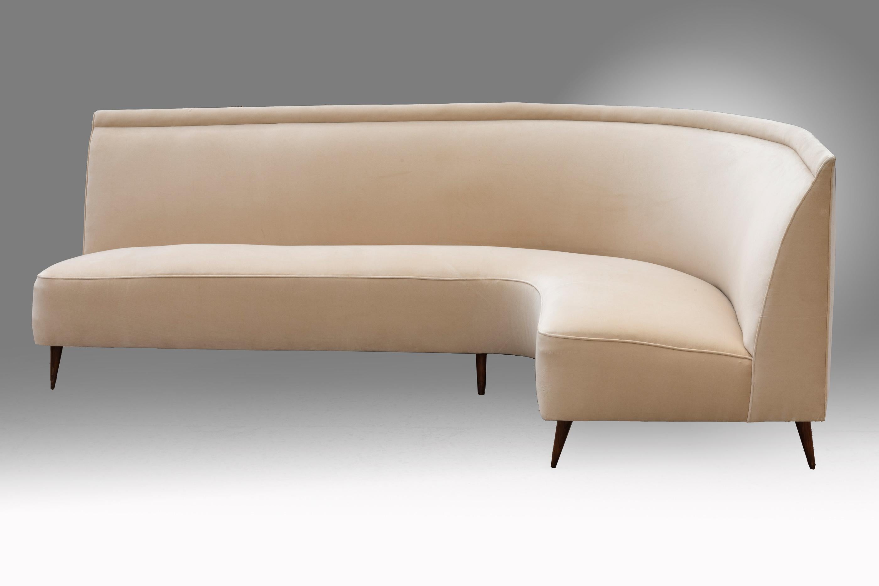 Iconic, elegant design for this curved shape sofa attributed to Italian architect Ico Parisi. The curved back envelope the seat. The frame sits on six conic wood legs. It is upholster with a cream 
