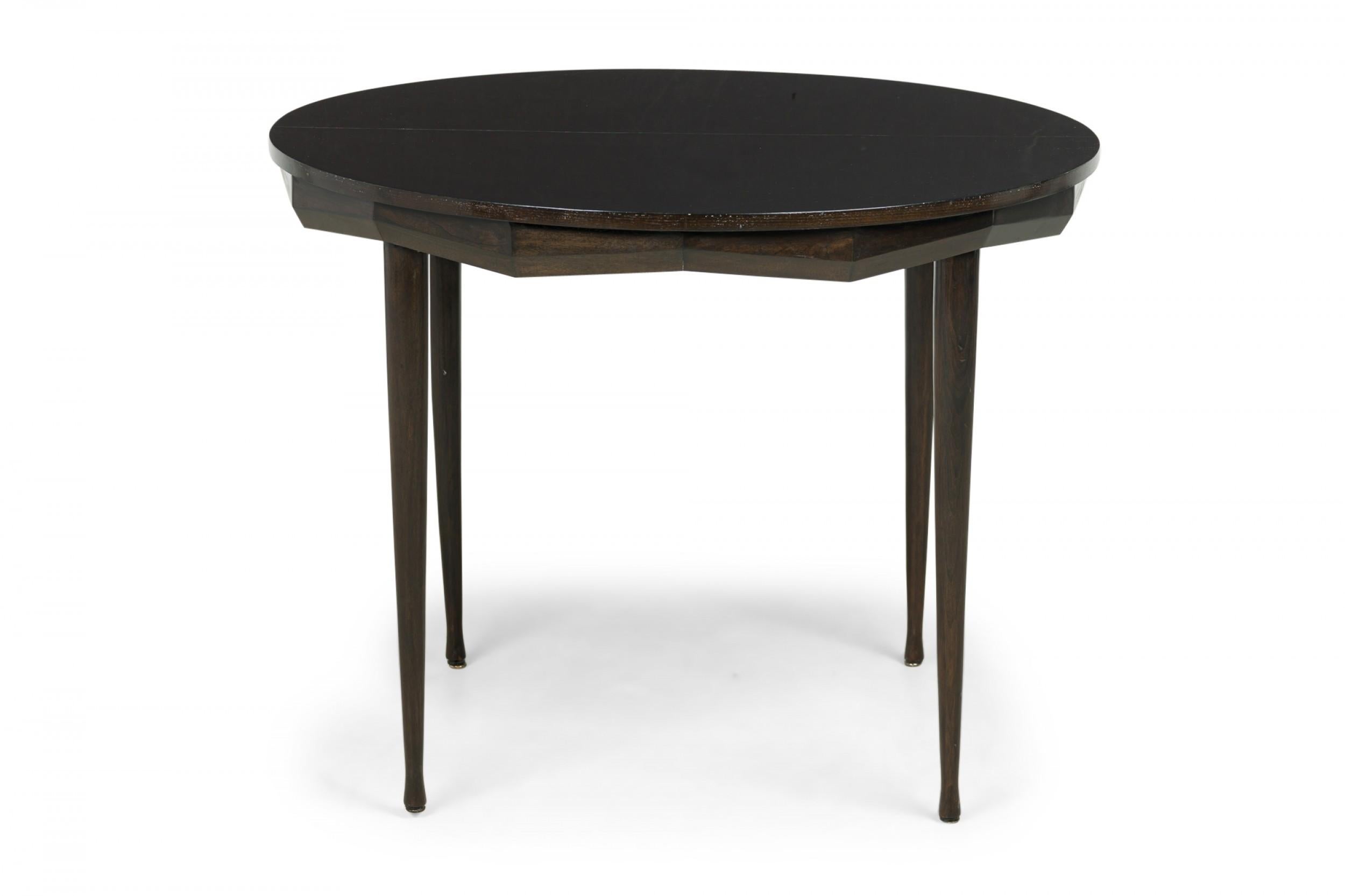Italian Mid-Century circular wooden center / dining / breakfast table in a dark finish, with a faceted apron and four tapered cylindrical legs. (ICO PARISI)
