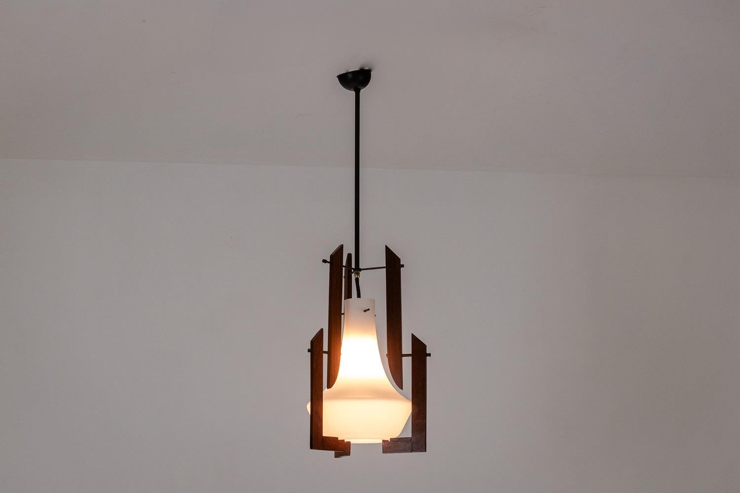 Ico Parisi, nello stile di.

Coppia di lampade a sospensione. Paralume opalino bianco circondato da forme di teak. Struttura in metallo laccato nero che termina con una tazza rotonda.

Opera italiana realizzata negli anni '1960.

Dimensioni: H. 78 x