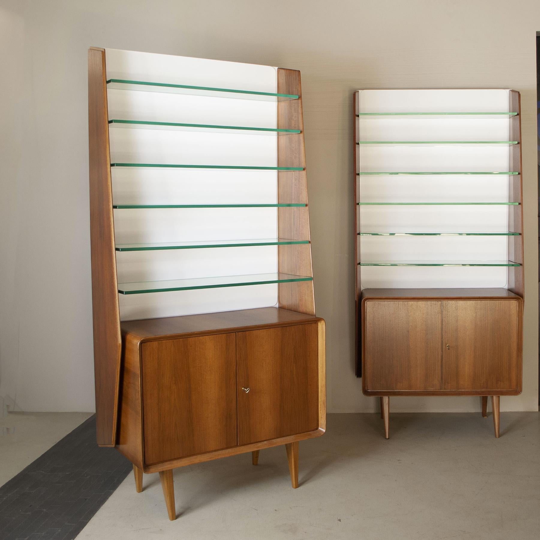 Pair of distinctive cabinets made of walnut wood with crystal shelves, a type of object that was often used by collectors to display their collections, the design can be traced back to Ico Parisi, produced in Italy in 1960 .

Ico Parisi was born in