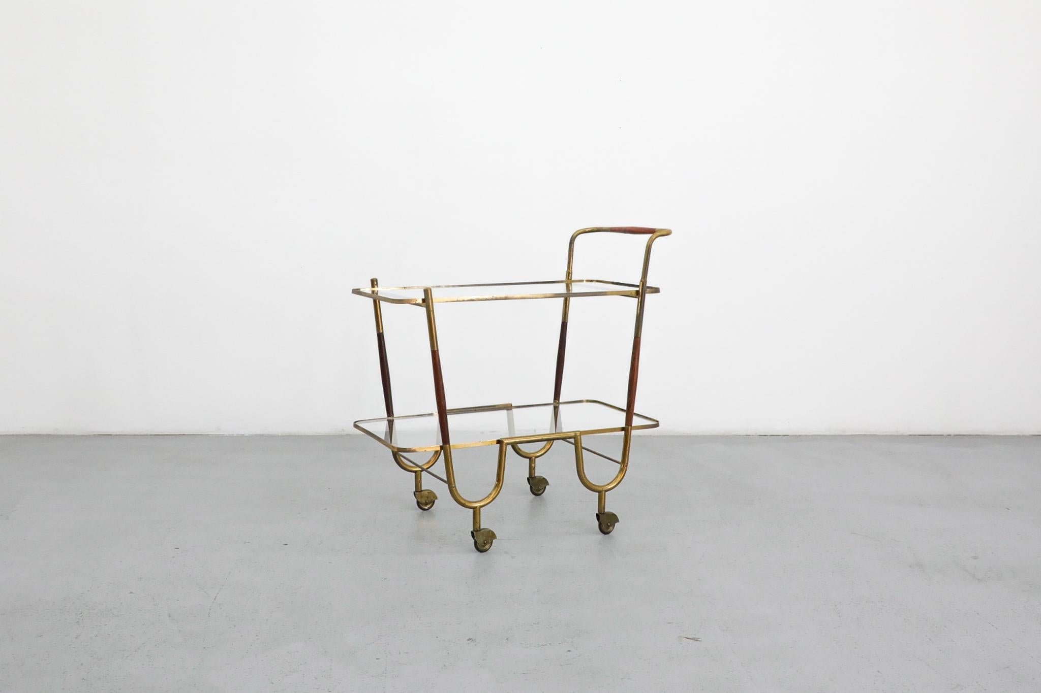 Chariot de bar ou chariot à thé en laiton, à deux niveaux, de style Cesar Parisi, créé par le designer italien Cesare Lacca. Ce magnifique chariot de service a un cadre tubulaire en laiton avec des accents en bois, des étagères en verre et des roues
