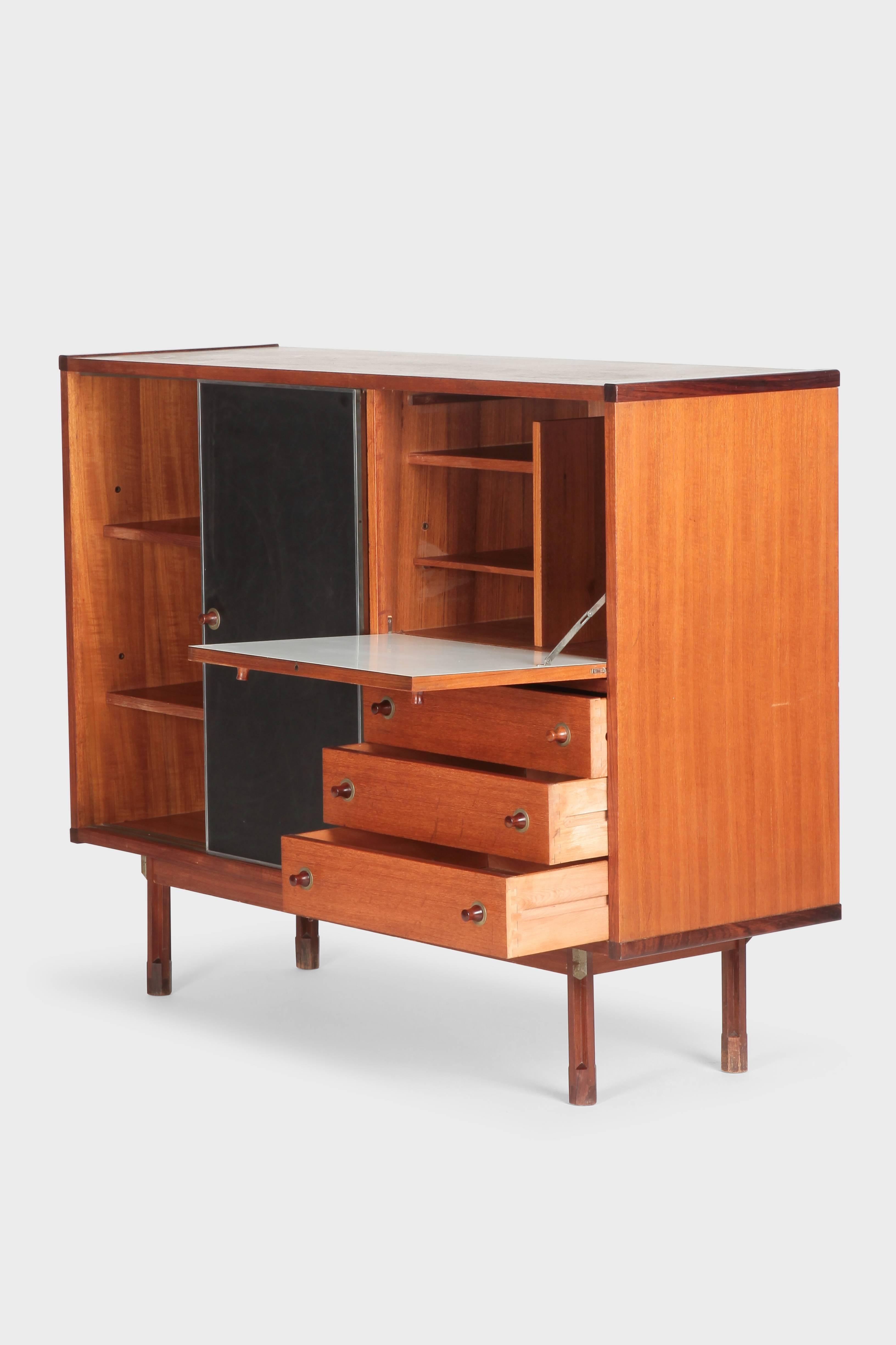 Ico Parisi highboard manufactured by Stildomus in the 1960s in Italy. Very varied teak highboard. Rosewood details like handles, feet and edges. Black plastic sliding doors framed with aluminium. The inside of the hinged door is covered with white