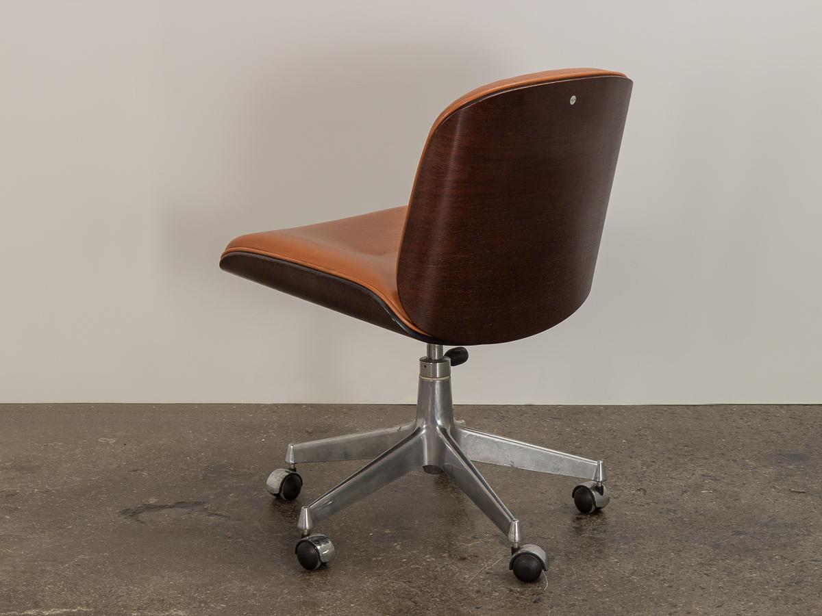 Terni series swivel office in cognac leather, designed by Ico Parisi for MIM Roma. An organic modern form made from curved bent rosewood that resembles shells. Brushed aluminum base with a smooth swivel function. Plump and bouyant seat is covered in