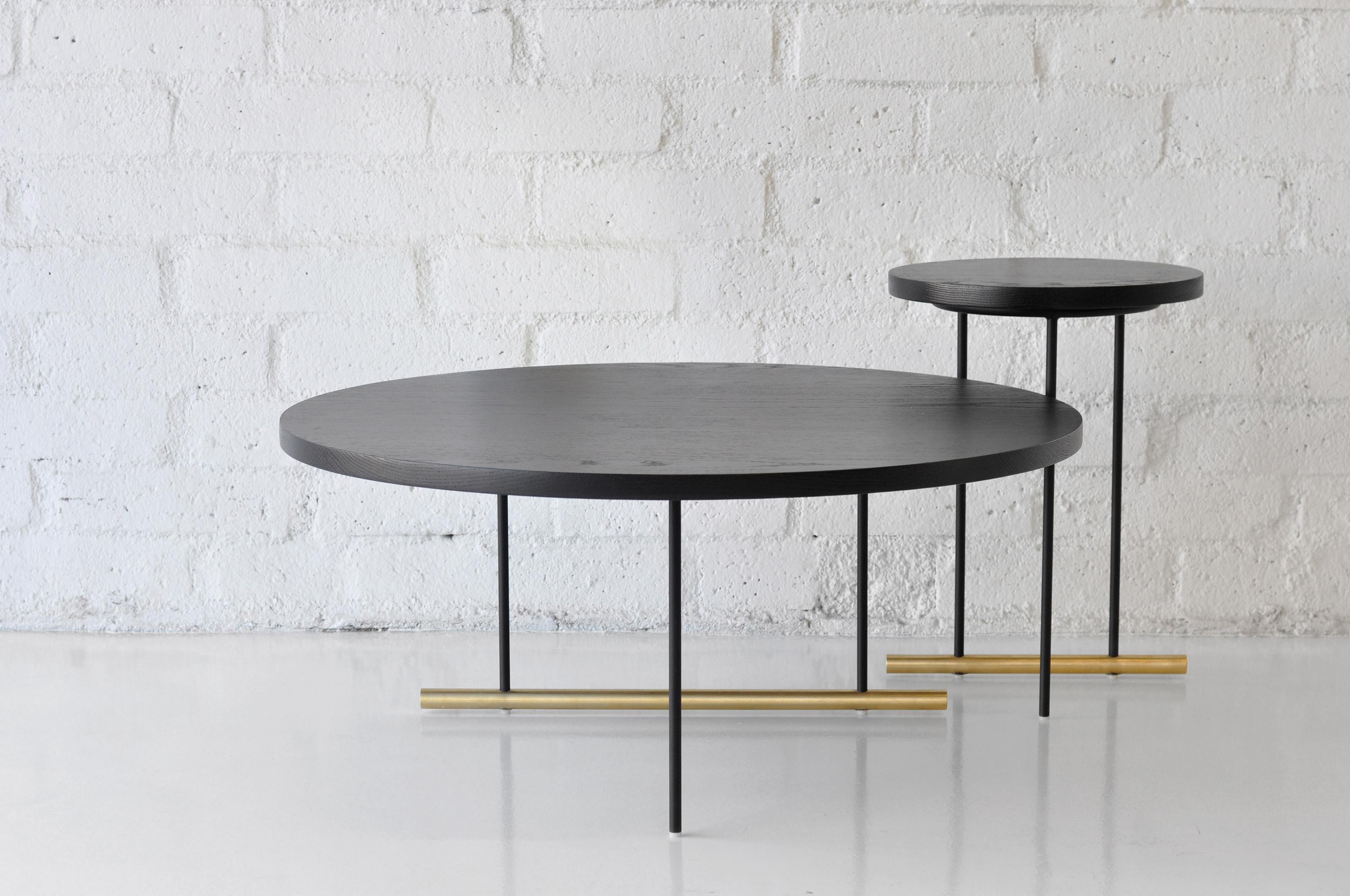 Suite of side, coffee, and dining tables comprised of a powder coated metal base with a solid brass detail, anchoring the tables. Tops can be sourced in glass, marble, and wood.

Prices exclude packing.

Pricing is for the Wood top version of the