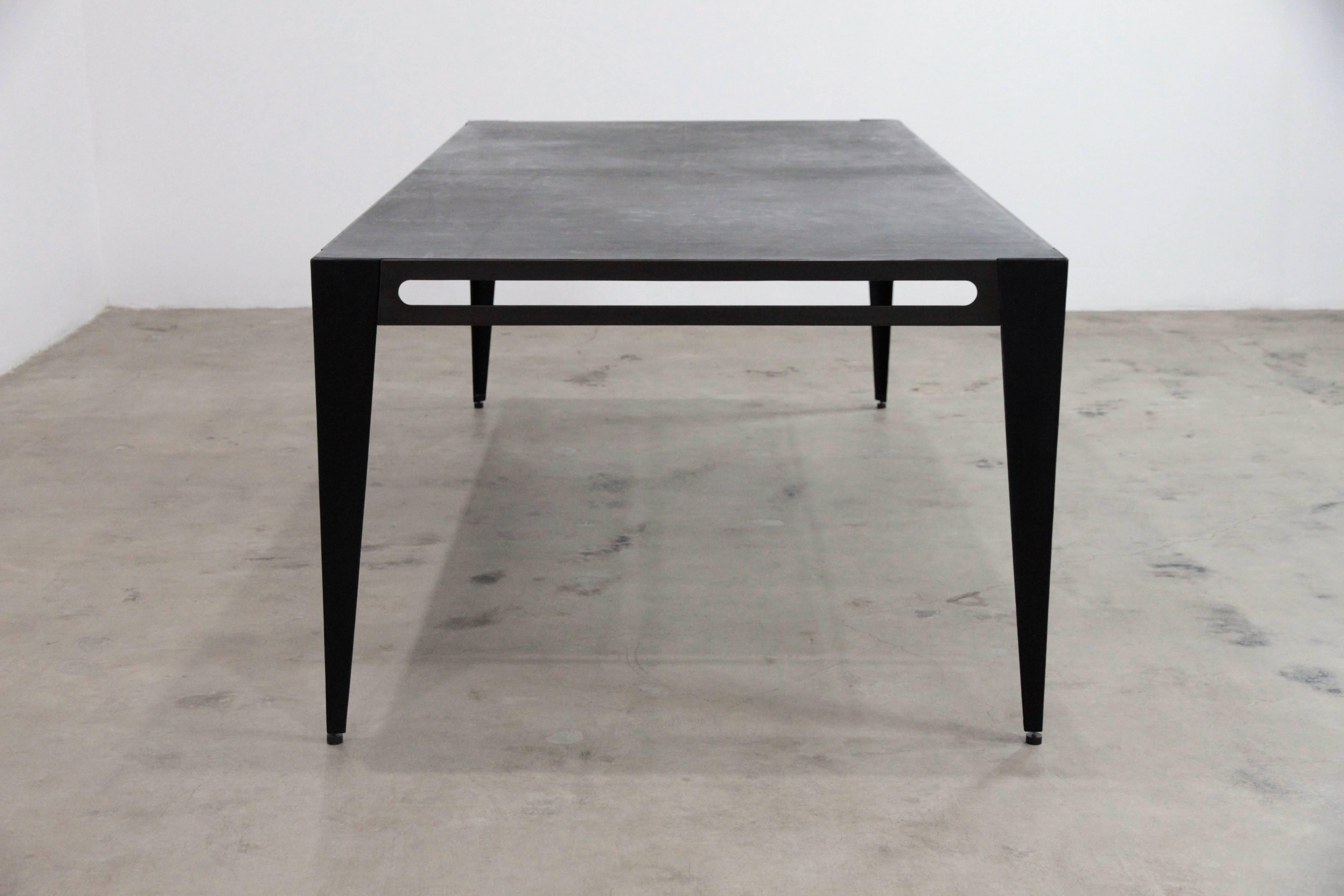 The Icon library table is steel with a bronzed patina. The legs are upholstered in hand stained lamb leather with adjustable feet. The Icon tabletop is upholstered with black saddle leather and black cashmere on the underside. Both the length and