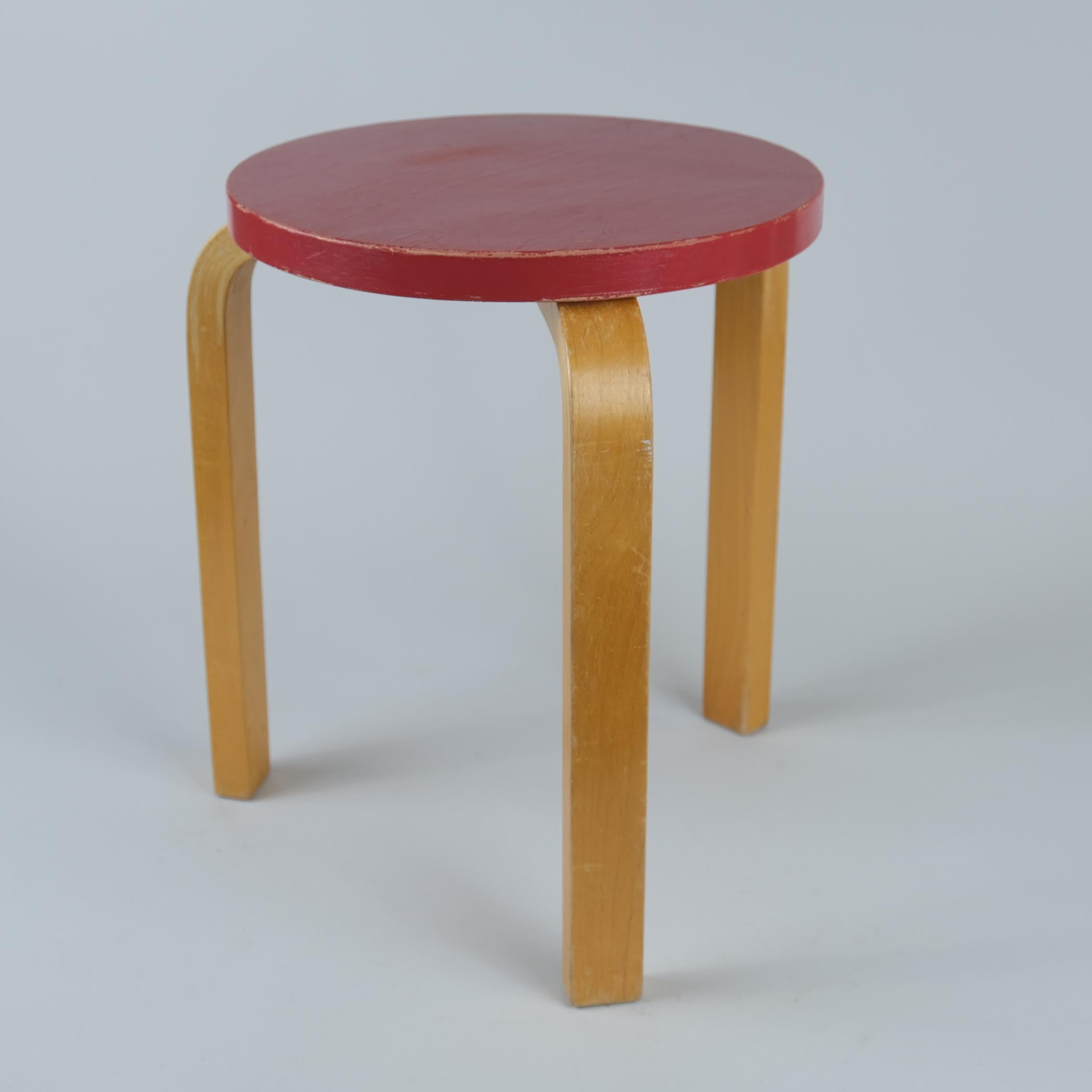 An iconic red model 60 stool in birch and beautiful patina. Designed by Alvar Aalto for Artek in the 1940s, this design has definitely stood the test of time, as it is still in production and still one of the most popular among consumers. The model