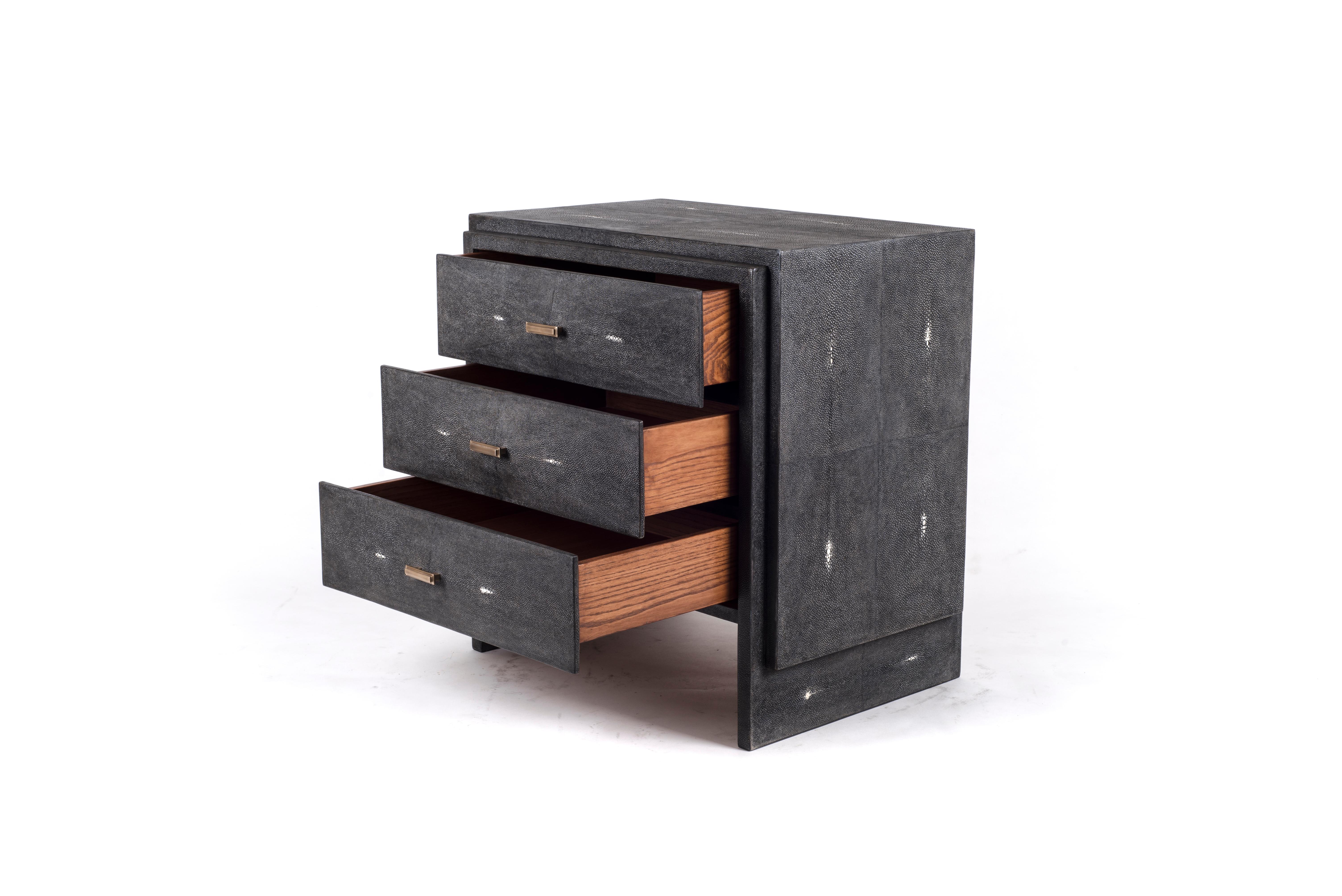 The iconic bedside by R&Y Augousti is one of their first designs. A classic and functional bedside table, with subtle geometry on the beveled drawers. This bedside table is completely inlaid in coal black shagreen with discreet bronze-patina brass