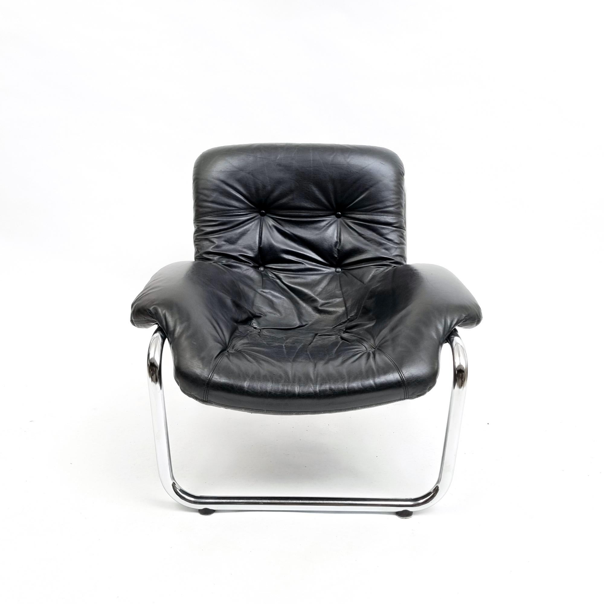A stunning vintage armchair, often attributed to Marcel Breuer and dating back to the 1970s. The chair boasts a chromed metal structure and black leather upholstery in excellent condition. With canvas ties and black leather armrests on chrome steel