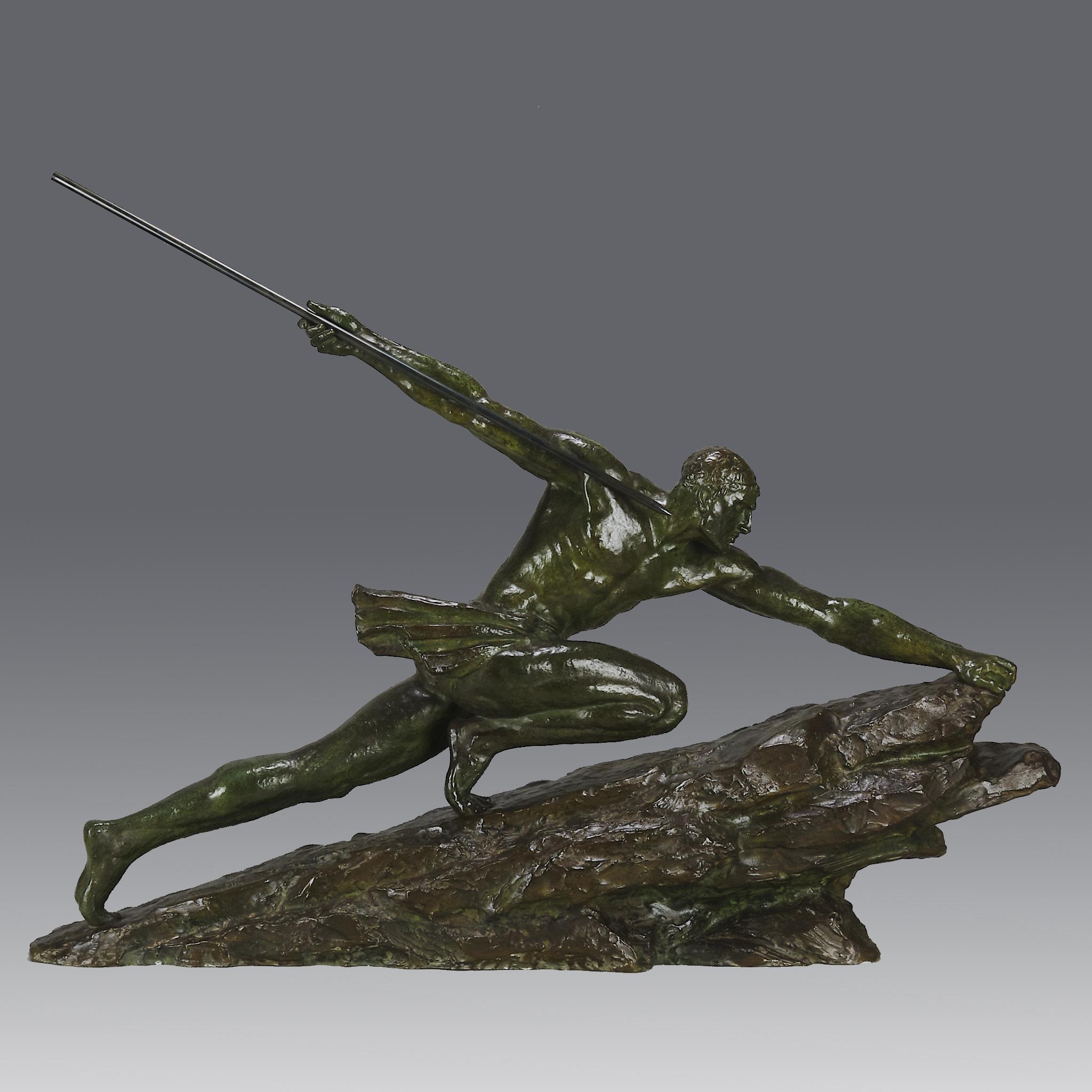 Eine ikonische, große Art-Déco-Bronzeskulptur eines starken, athletischen Mannes in kraftvoller Pose, der einen langen Speer in der Hand hält, während er einen großen Felsblock erklimmt. Die Bronze ist von herrlich satter grüner Farbe und