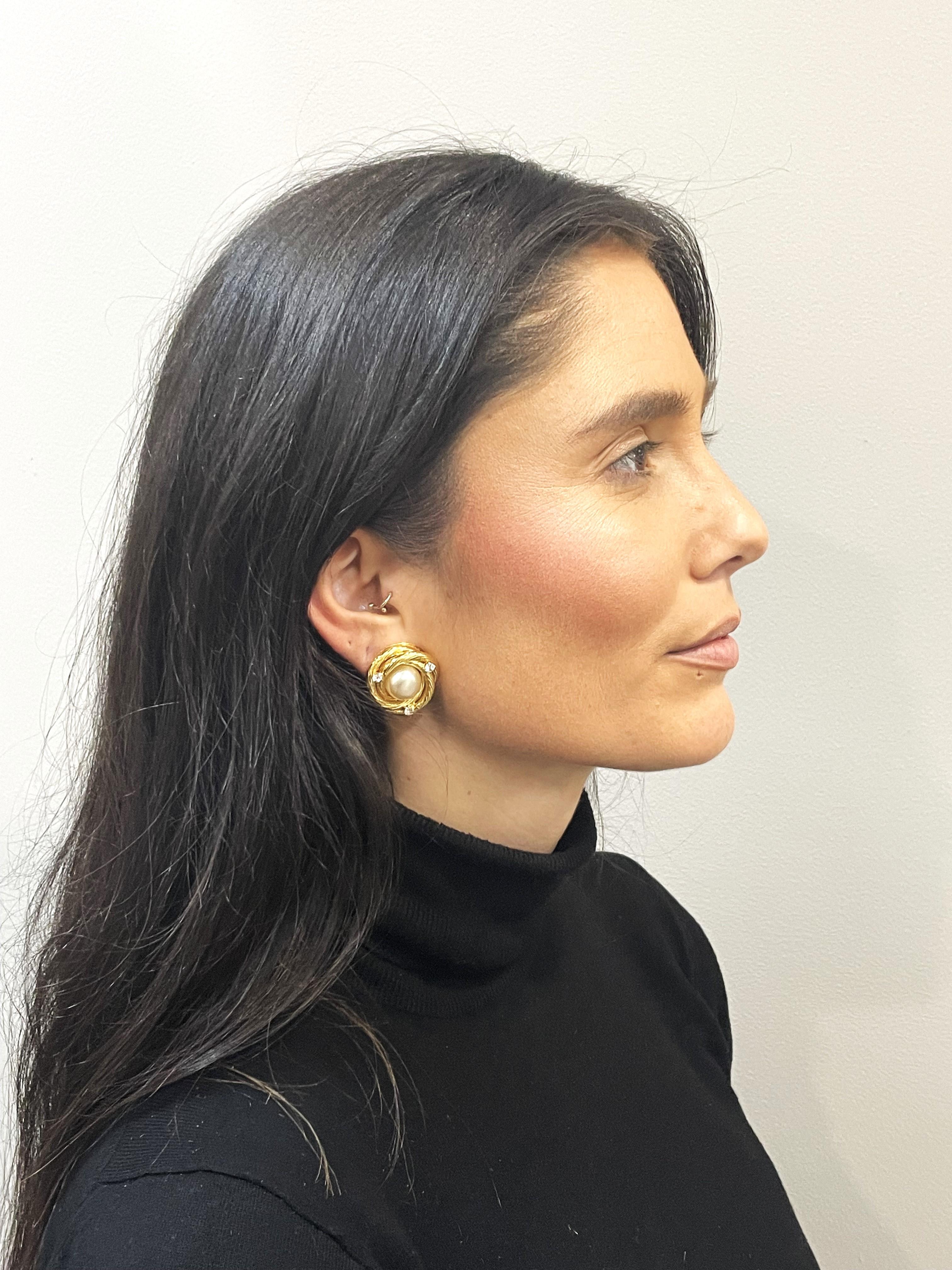 Iconic gold plated CHANEL CLIP-ON EARRING,
In the middle there is a hand-crafted pearl that is wrapped with the typical Chanel cord and decorated with 3 small rhinestones. 

Measurement
Diameter of the round Chanel ear clip is 2.5 cm, diameter of