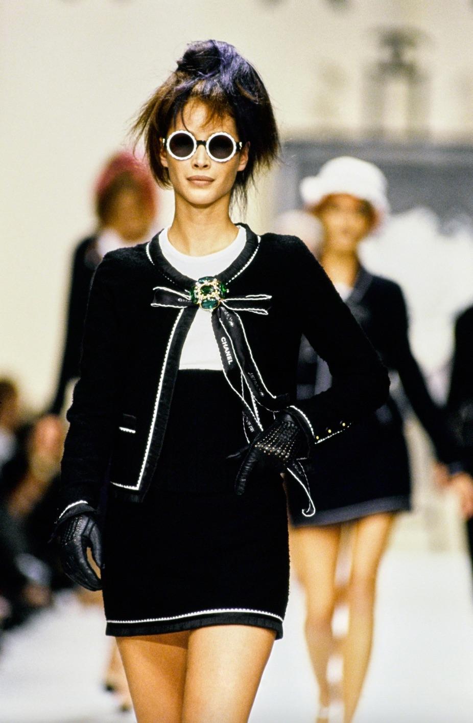 Voici une pièce intemporelle de la collection Chanel printemps/été 1994 : le tailleur en laine marine. Cet ensemble, présenté dans divers magazines et porté par des icônes de la mode comme Christy Turlington et des célébrités telles que Jennie,
