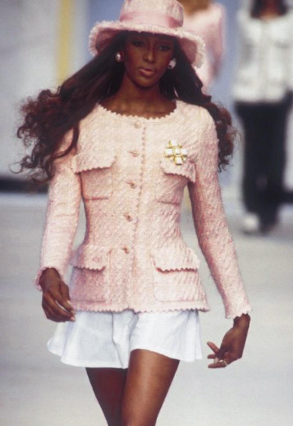 This extremely rare pink tweed jacket from Chanel's 1993 Spring collection is a piece of fashion history. Seen on the iconic Naomi Campbell, this jacket embodies the aesthetic of nineties fashion. The tweed fabric boasts a soft pink hue, four