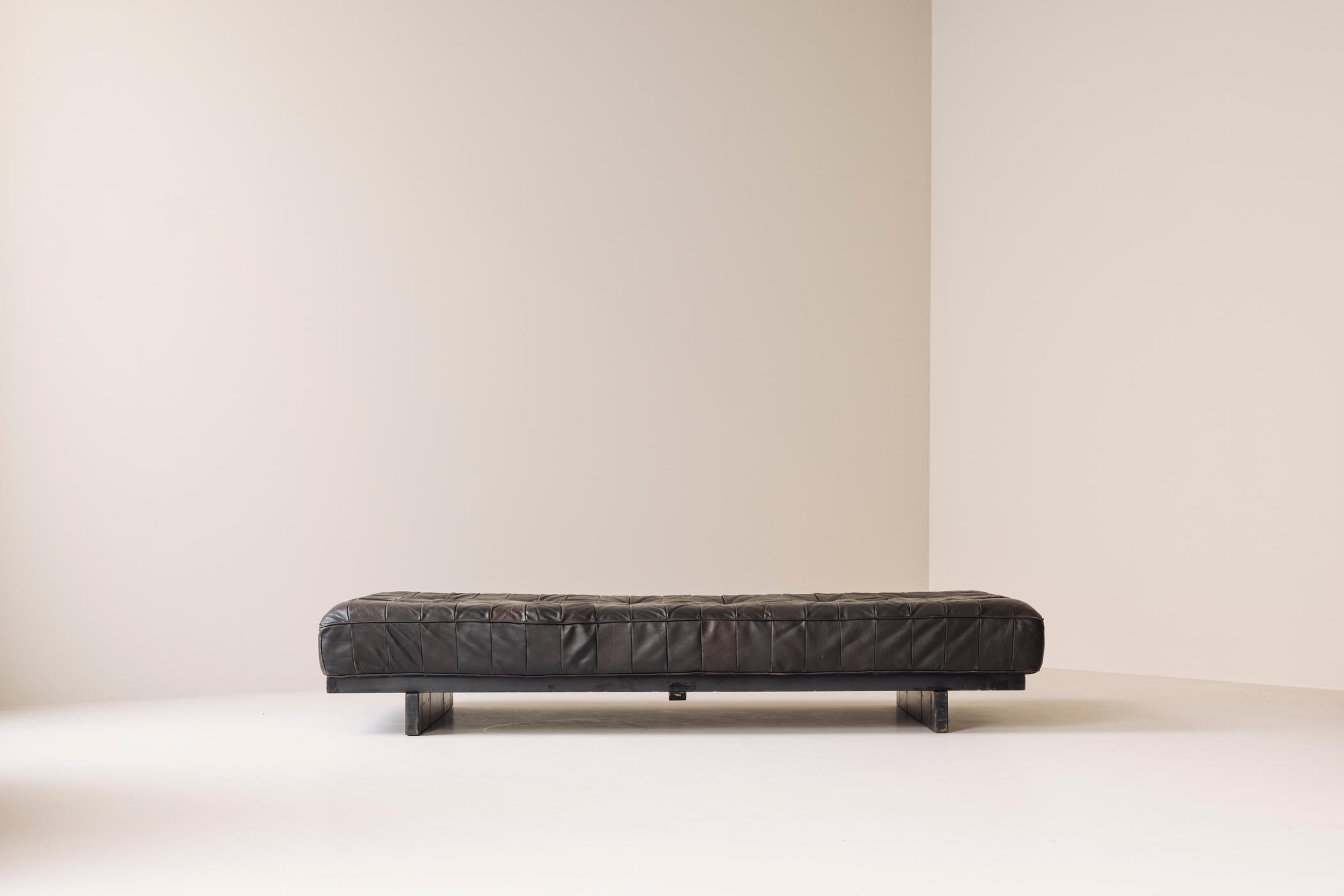 Iconic DS-80 daybed by De Sede, Switzerland 1970s. This vintage leather patchwork sofa is upholstered in rich, dark brown leather. It features a beautifully aged patina, adding depth and warmth. Designed with a minimalist aesthetic, this
