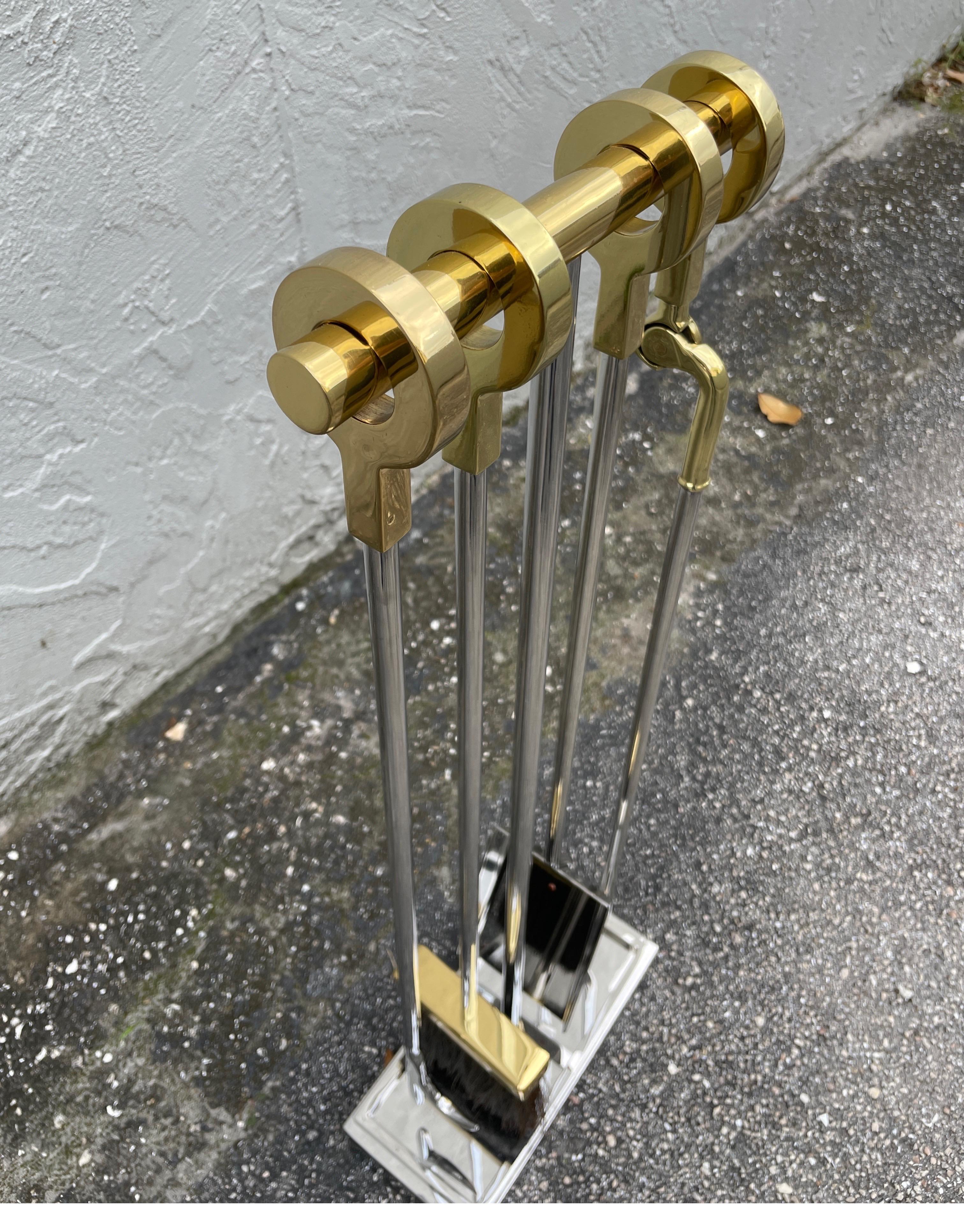 Iconic set of polished chrome and brass fireplace tools consisting of five pieces in excellent condition. There is another listing with matching Andirons also in polished chrome & brass.