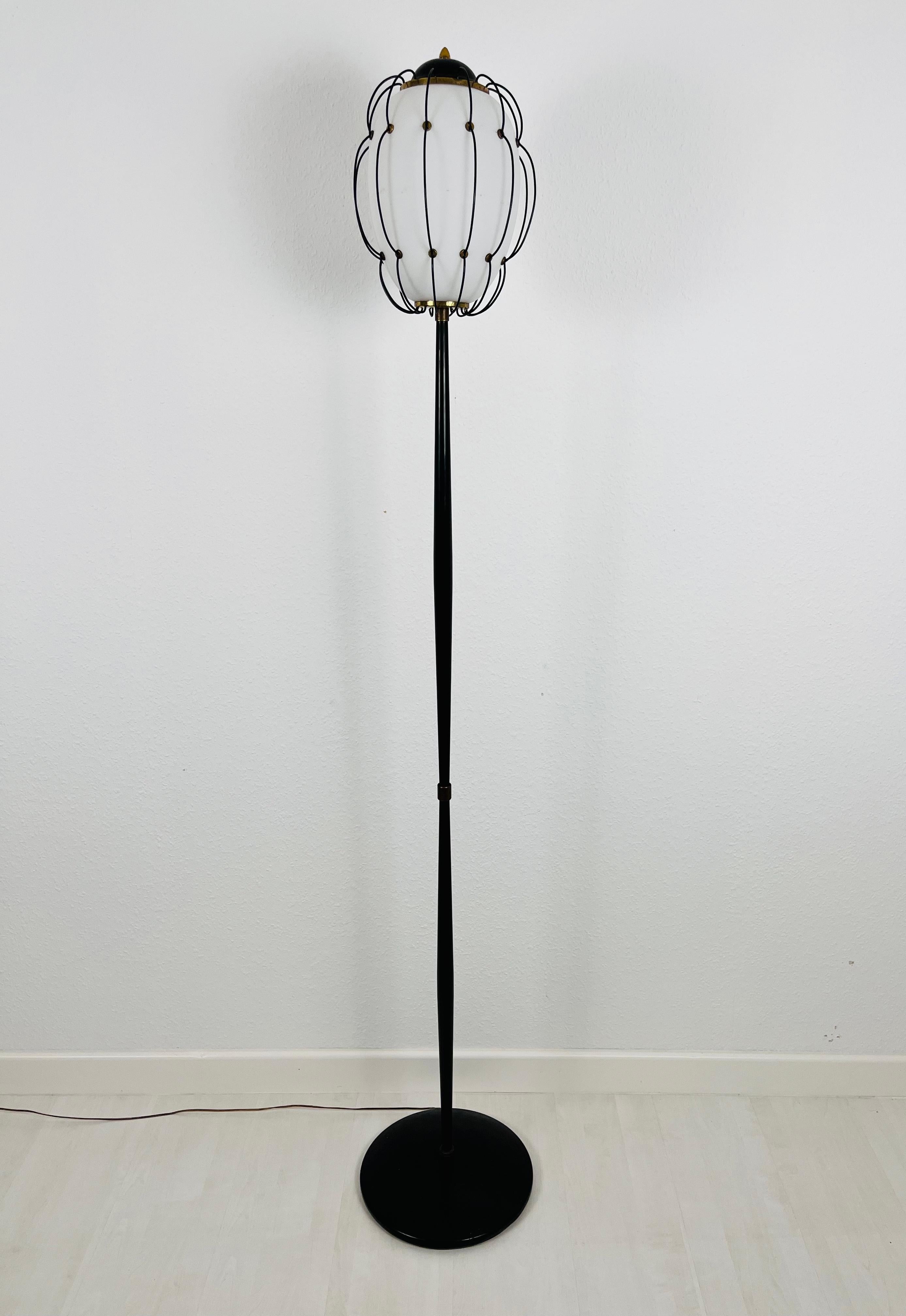 Iconic floor lamp designed by Angelo Lelli for Arredoluce in the 1950s. Round metal base with an elegant minimalist rod. Beautiful opaline glass surrouned by metal and brass ornaments.

The light requires one E27 (US E26) light bulb. Works both