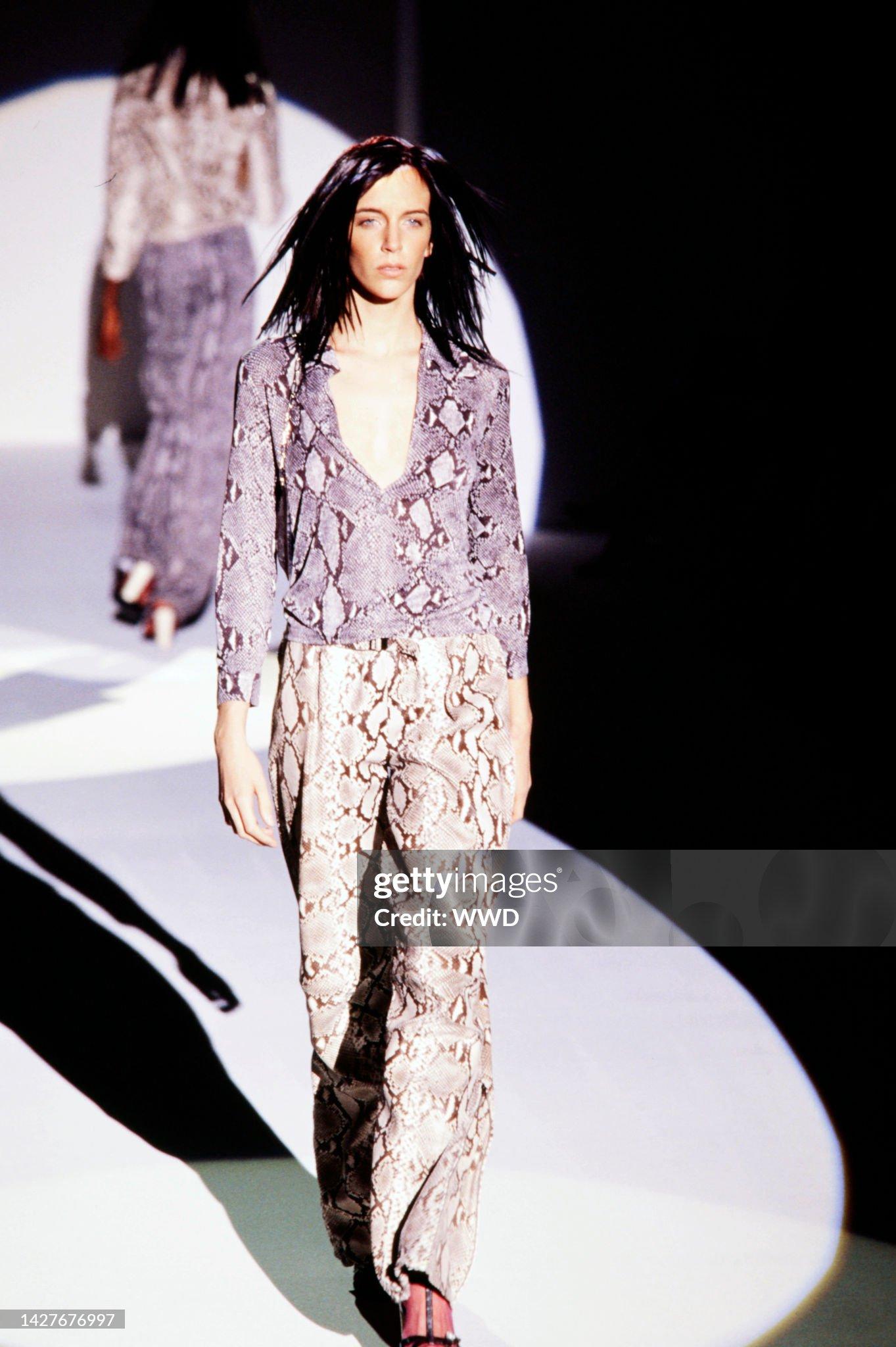 Gucci by Tom Ford 2000 Gucci trousers with snakeskin print. 

Gucci Spring 2000 Ready to Wear Runway Show - Model Hannelore Knuts


There is an italicized Gucci inscription all over the picture. 
Flared leather trousers with a high fit. 

The length