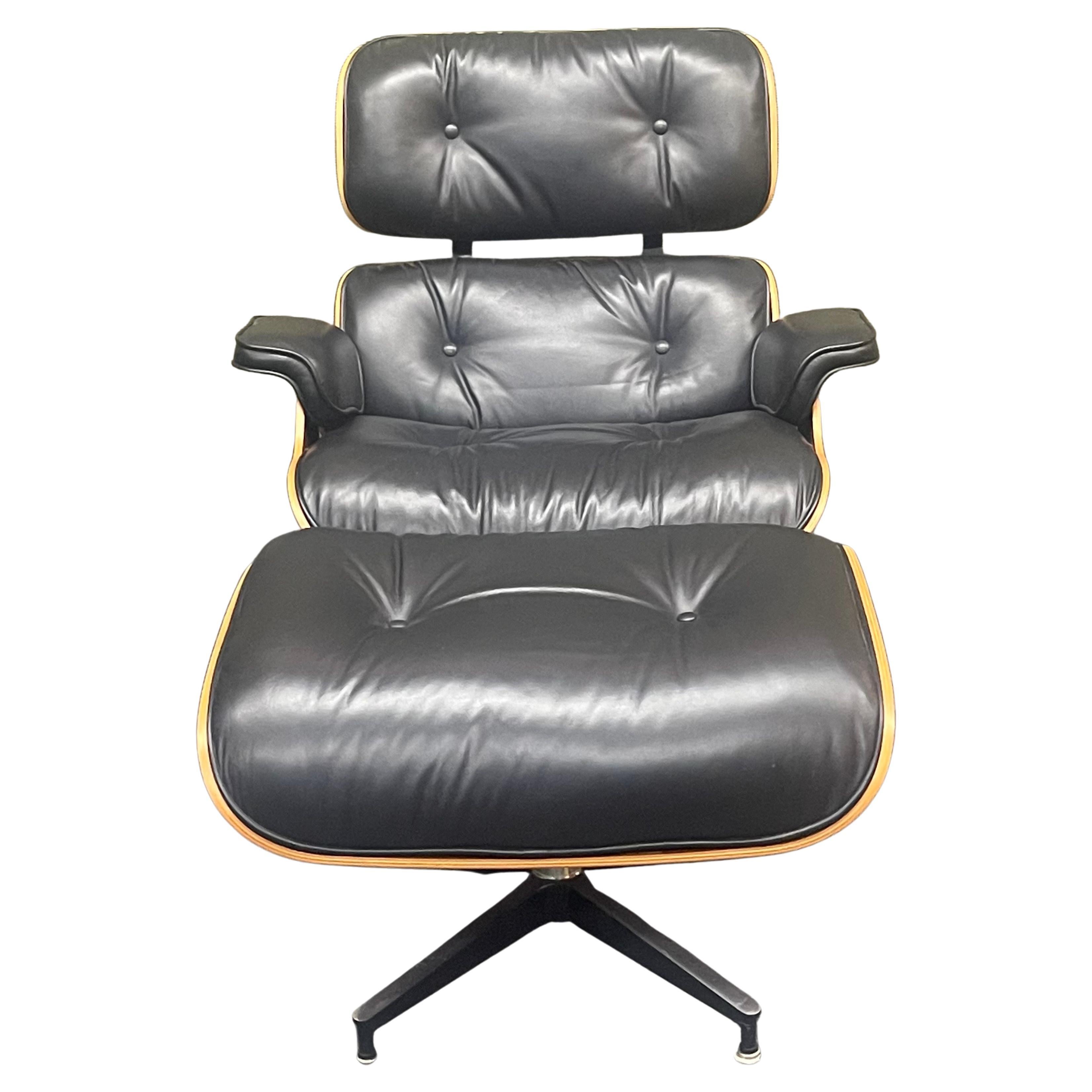 Authentique et iconique chaise de salon et ottoman Herman Miller / Eames en noyer et cuir noir (modèles 670 & 671), circa 2004. L'ensemble est légèrement usé et en bon état (à l'exception d'une petite éraflure sur le cuir de l'assise de la chaise).