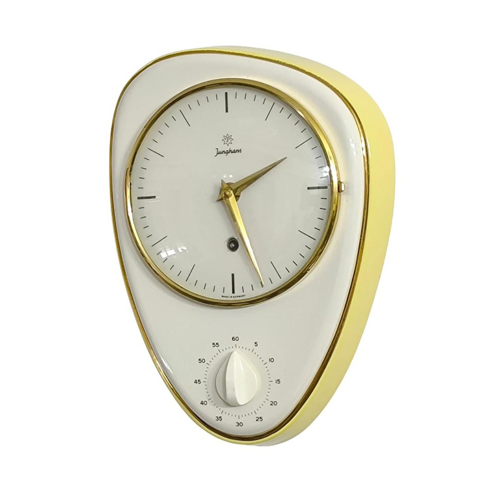 Importante orologio da cucina modernista in ceramica smaltata disegnato da Max Bill per Junghans, Germania 1956, con timer da 60 minuti, movimento meccanico a 8 giorni, cassa in ceramica bianca e gialla con bordo dorato a forma di rene, vetro a