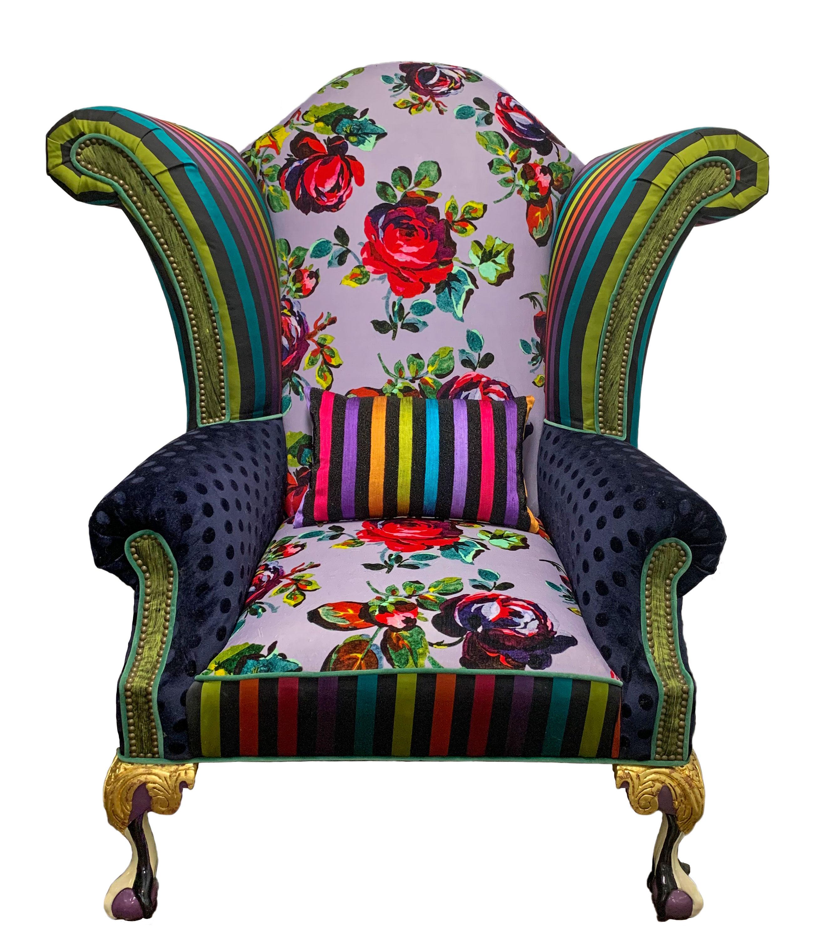Iconic Mackenzie-Childs monumental armchair in zany eye-popping florals, stripes and dots. Upholstered in luxurious textural fabrics with hand carved claw-foot legs that are gold-leafed and hand painted by their artisans in Aurora, New York.