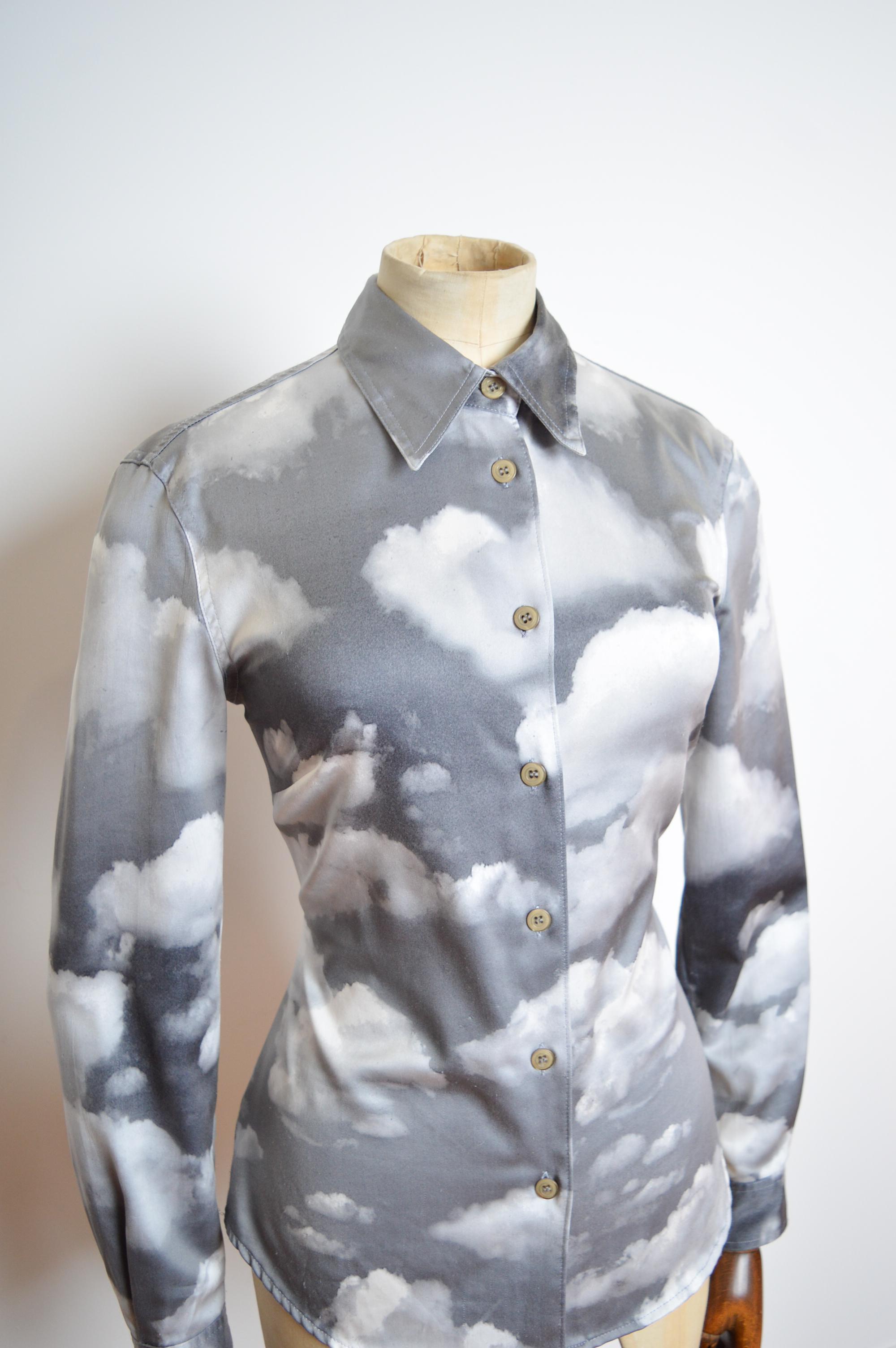 Iconica camicia Moschino degli anni '90 con stampa Sky Cloud grigia, aderente 
MADE IN ITALY. 
Corpo aderente, Bottoni sul davanti, Maniche lunghe. 
Da fossa a fossa: 17,5