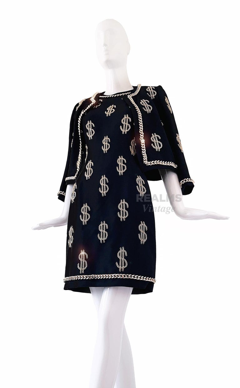 $$$ MOSCHINO Couture $$$
Absolutely amazing two piece ensemble: black dress and jacket with heavy high quality gold coloured metal Dollar Signs and chain details.
Super iconic and famous Moschino Design. Super elegant tailoring with the typical