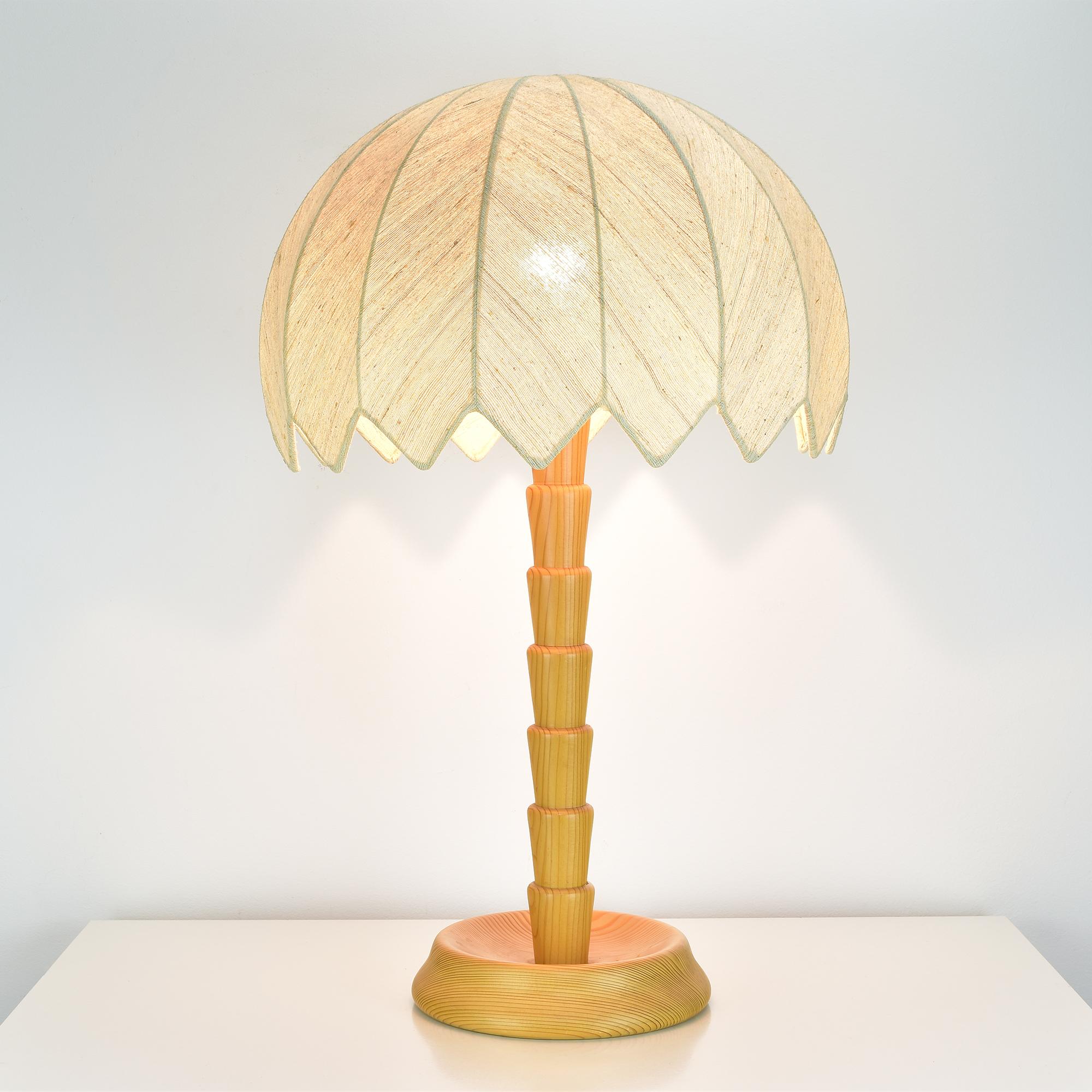 This charming Temde table lamp from the 1960s brings a touch of tropical elegance to any interior. 
Its pinewood base and stem are crafted to resemble a stylized palm tree, exuding mid-century modern charm with a natural flair. 
The dome-shaped